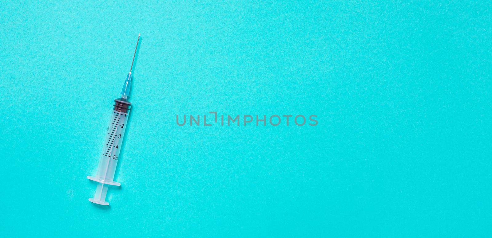 Syringe on pastel blue background from above by Ciorba