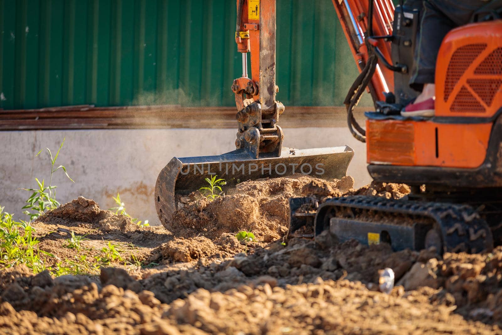 A minitractor rakes the earth with a bucket. Land works