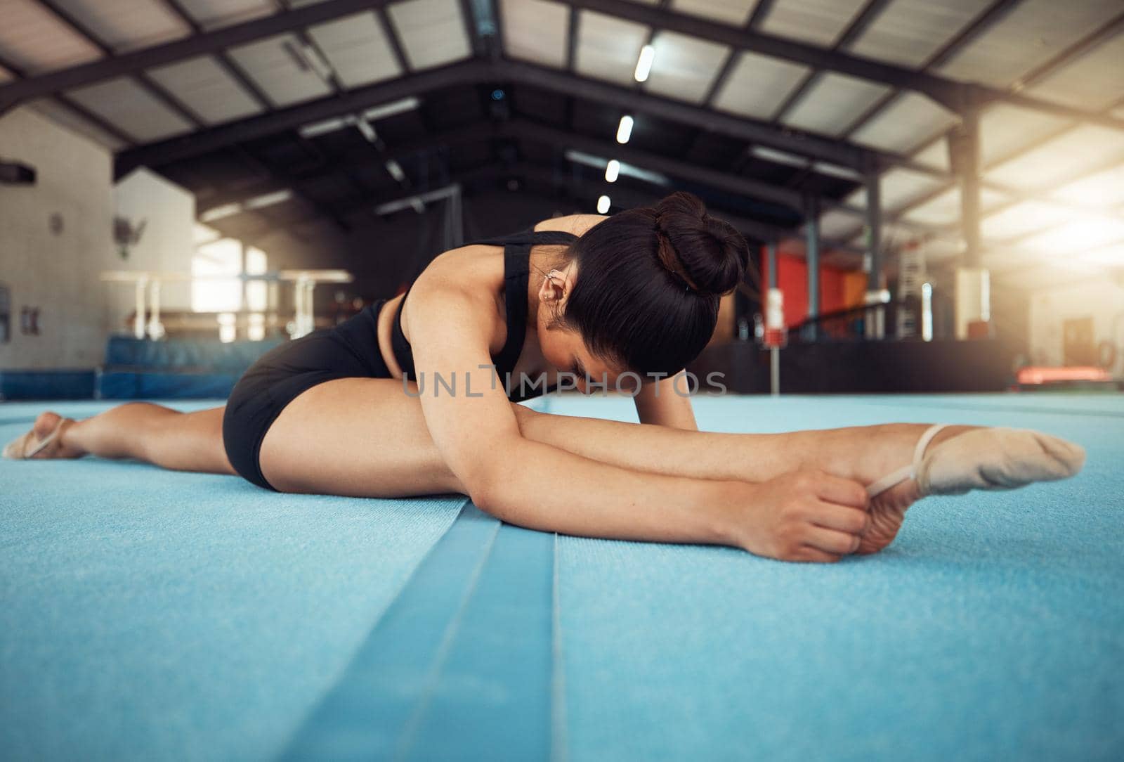 Sports woman stretching on the floor in yoga splits in a gym. Young fitness girl or athlete legs in training, workout exercise or cardio with motivation, wellness and commitment for a competition.