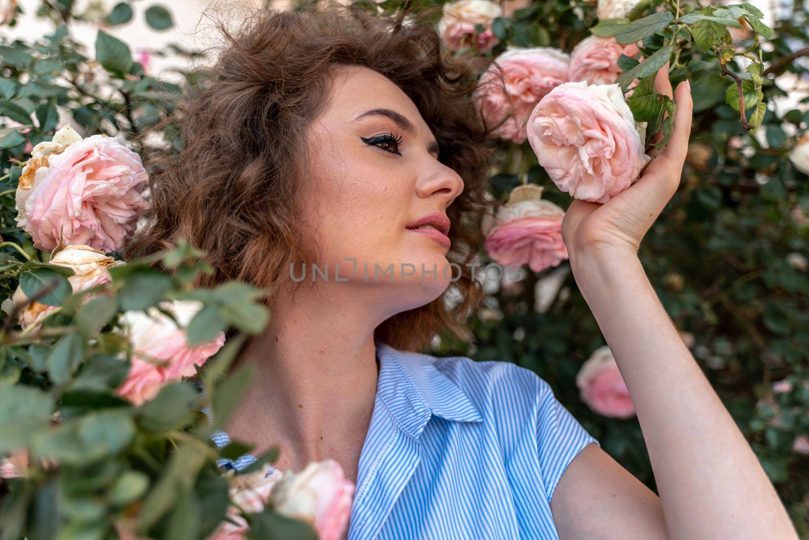 Portrait of a young woman in spring. Flowers of pink roses bloom