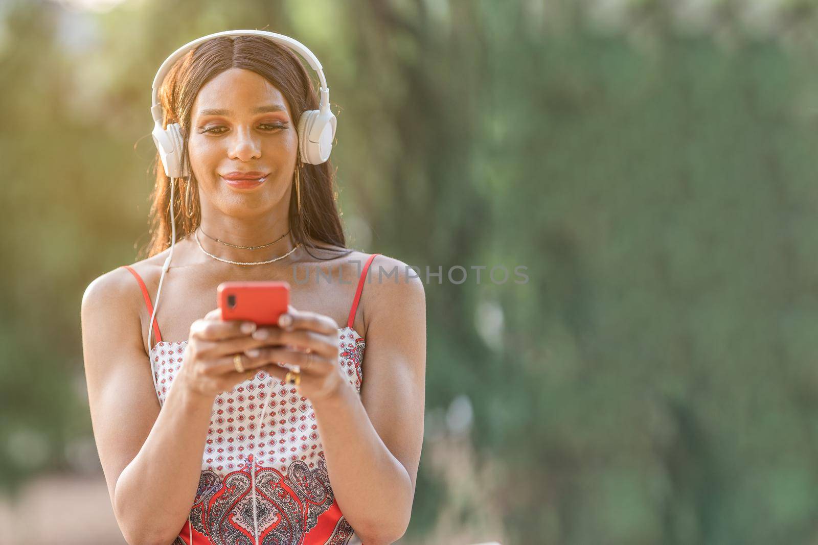 Portrait with copy space of a Transgender woman listening to music with the mobile outdoors