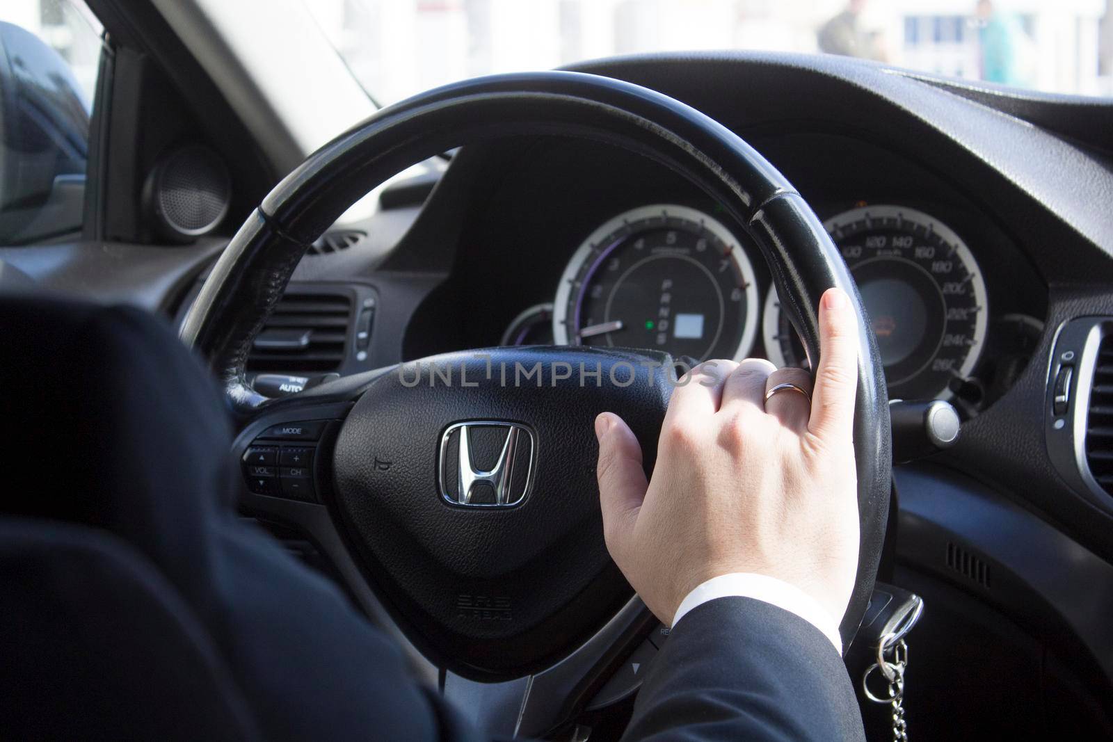 Businessman in a presentable luxury car, Honda. On the steering wheel of a Honda man's hand in a suit.