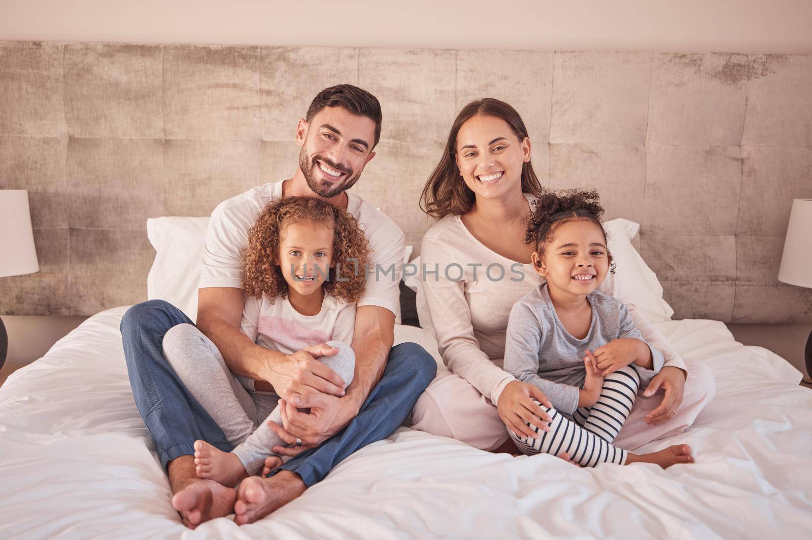 Family portrait on bed and happy mother, father and children wake up in the morning together with happy smile on face in their bedroom home. Happiness of mom and dad with kids while they relax.