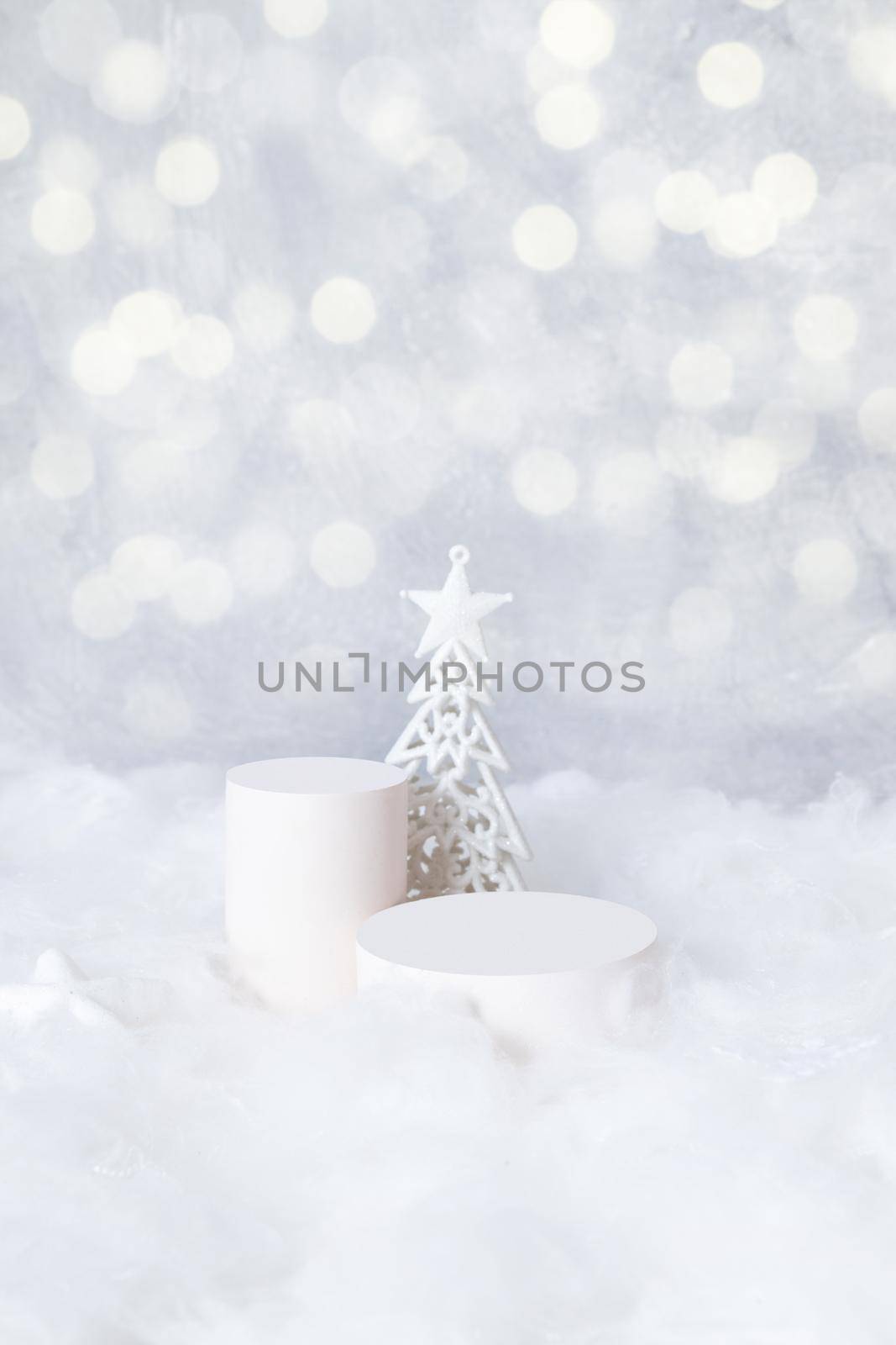 Podiums mok-up for cosmetics in the snow with a christmas tree on a bokeh background vertical format.