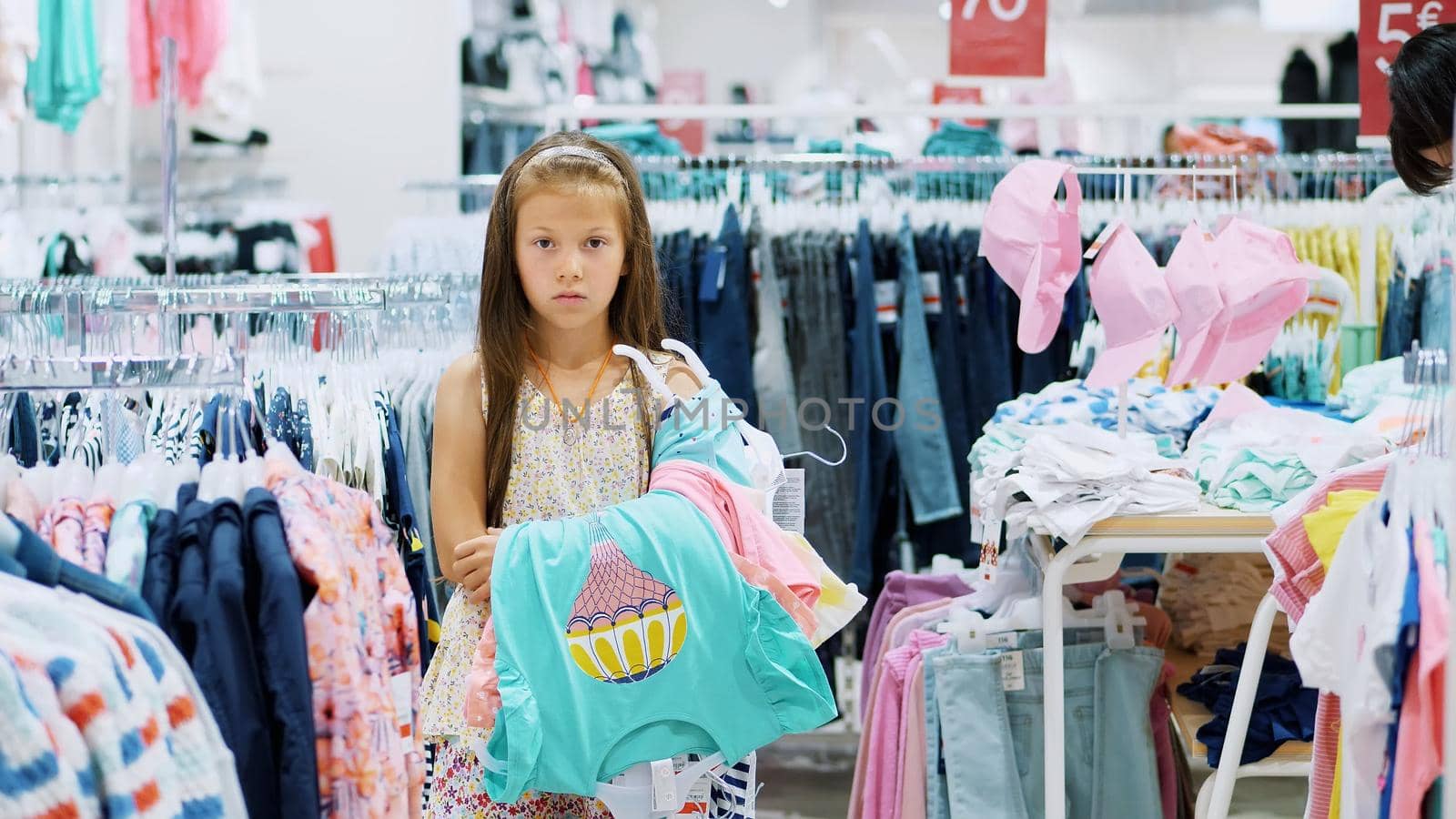 tedious shopping in stores. tired, sad kid, girl, with a bunch of things in their hands, waiting for parents in the store. High quality photo