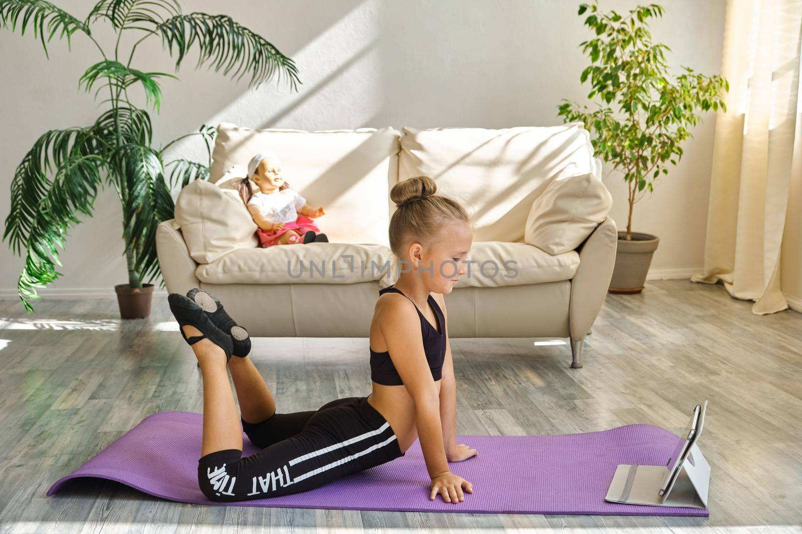 Kid repeating exercises while watching online yoga gymnastics session by InnaVlasova