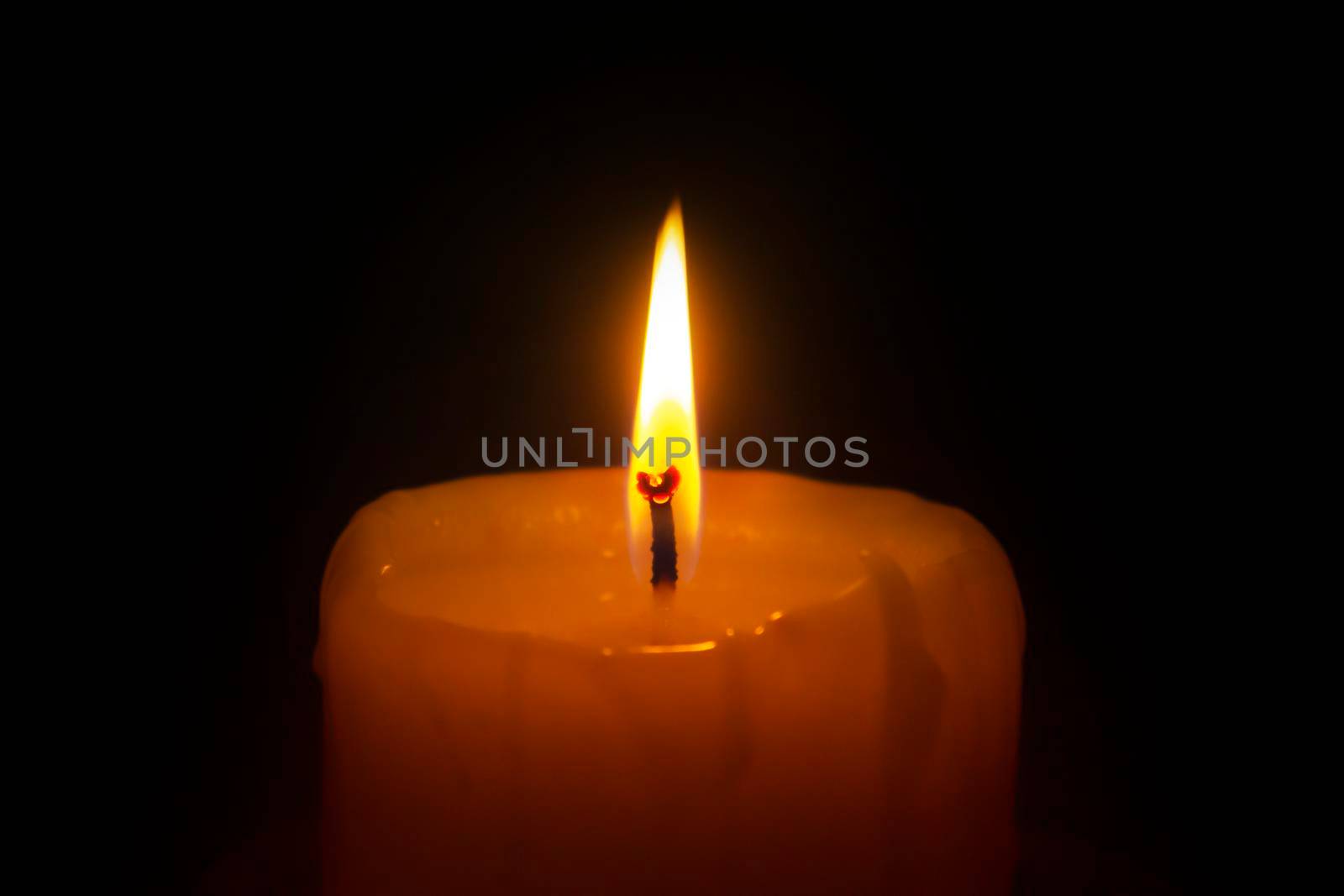 Candle light on black background close up. Glowing flame for Christmas, holidays and religion event decoration.