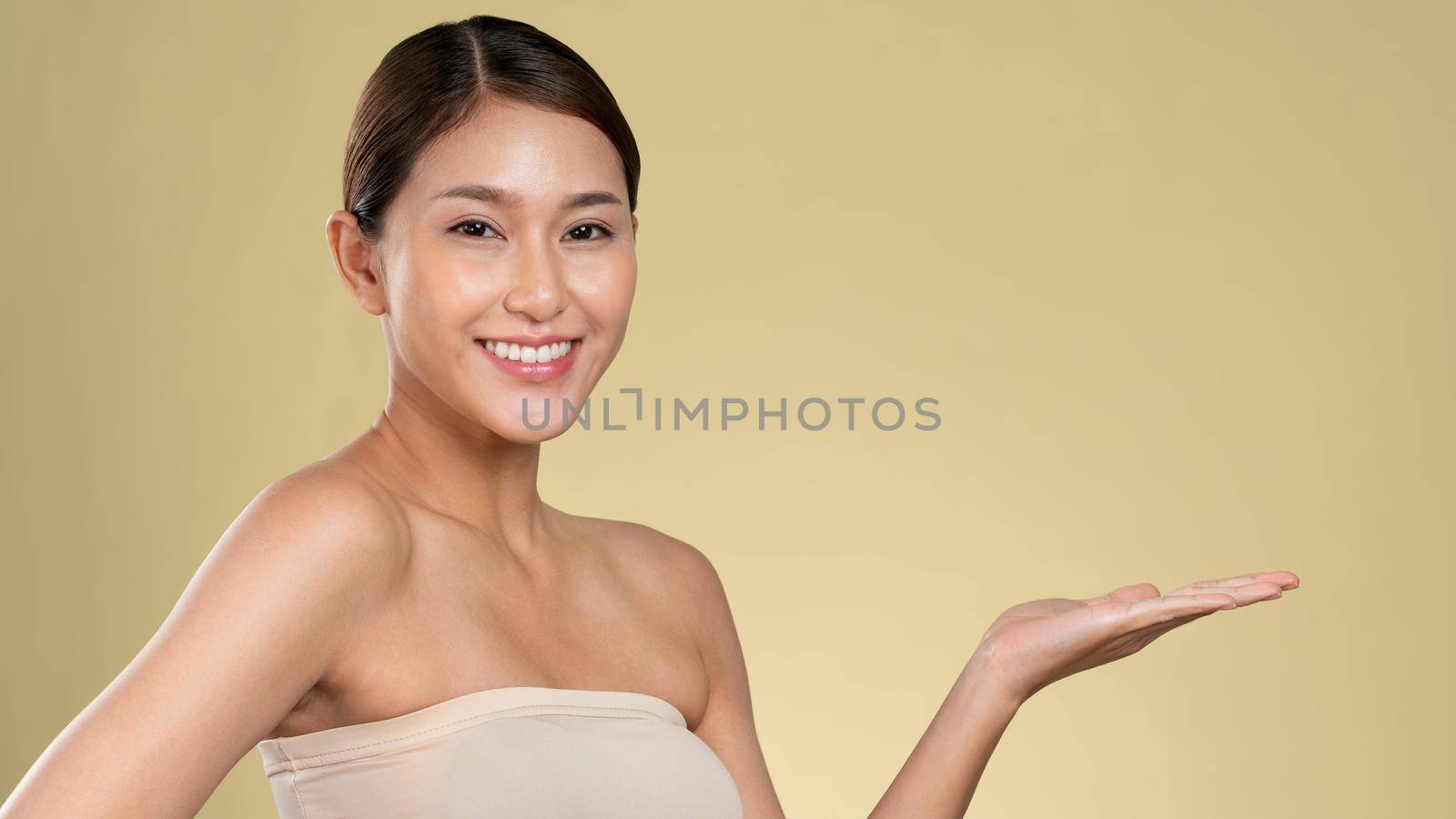 Closeup ardent woman looking at camera, holding empty space for product, advertising text place, isolated background. Concept of healthcare advertising for skincare, beauty care product.