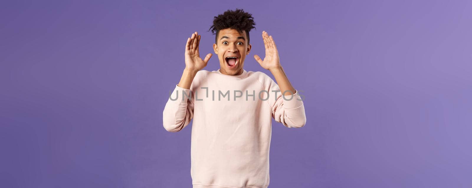 Portrait of happy surprised young man, celebrating birthday, open his eyes to see something really awesome, receive incredible gift, being astounded and speechless from joy and happiness.