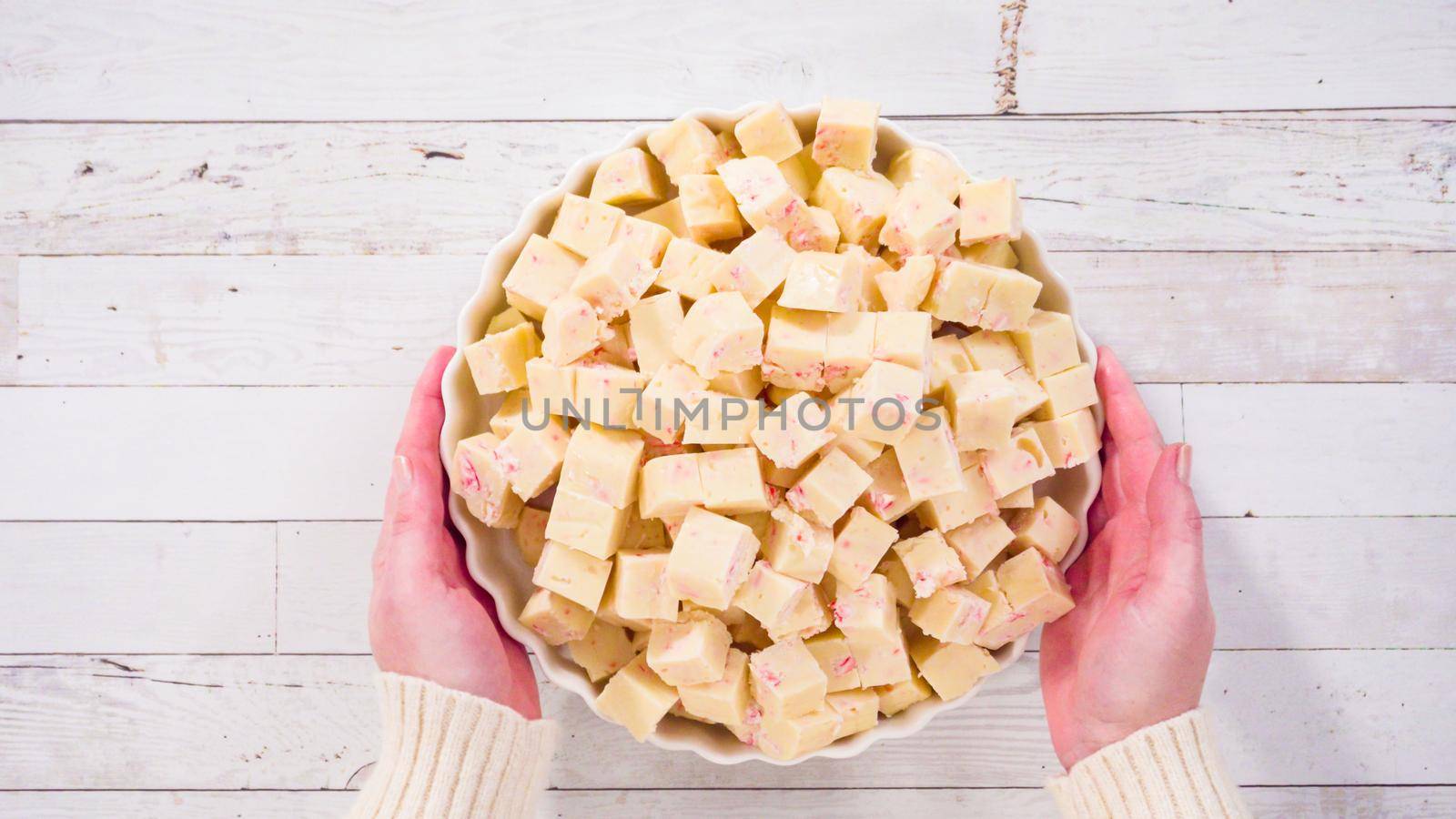 Flat lay. Step by step. Candy cane fudge cut in small cubes on a white serving dish.