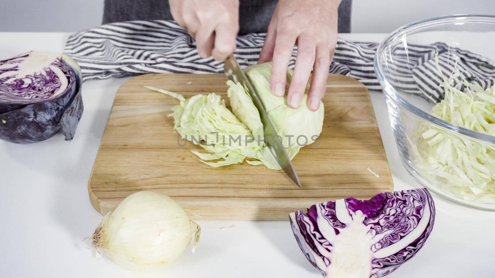 Step by step. Shredding organic cabbage on a wood cutting board.