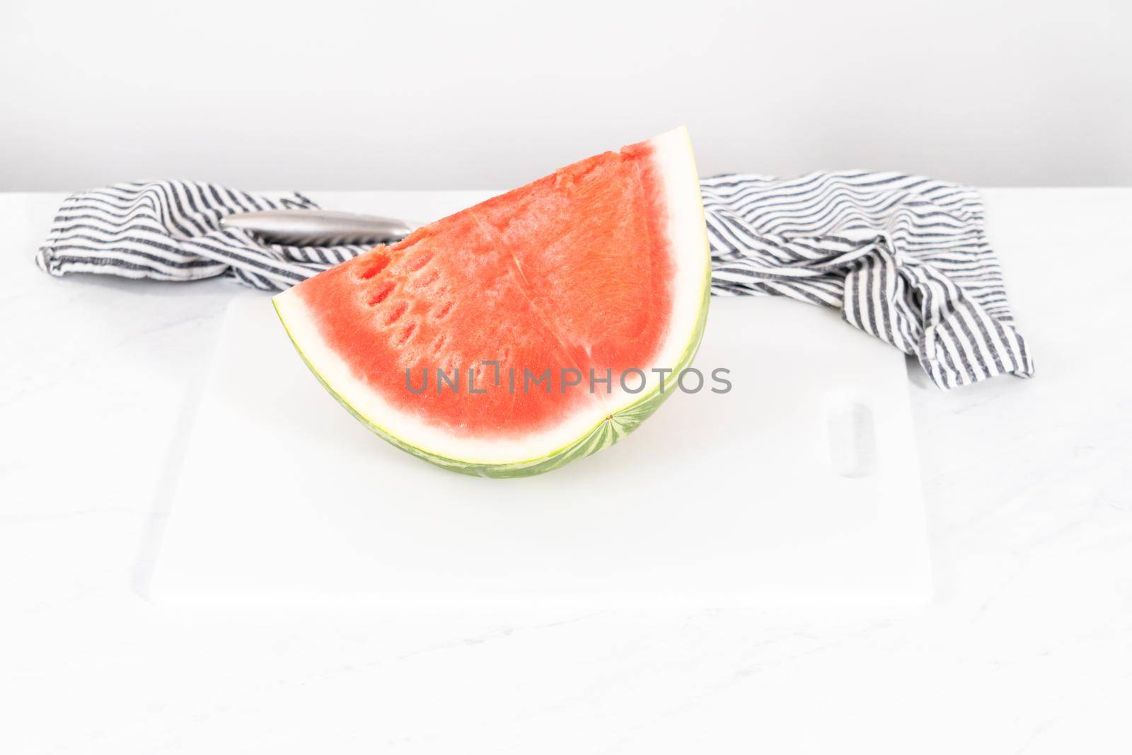 Cutting riped red watermelon to prepare frozen watermelon margarita.