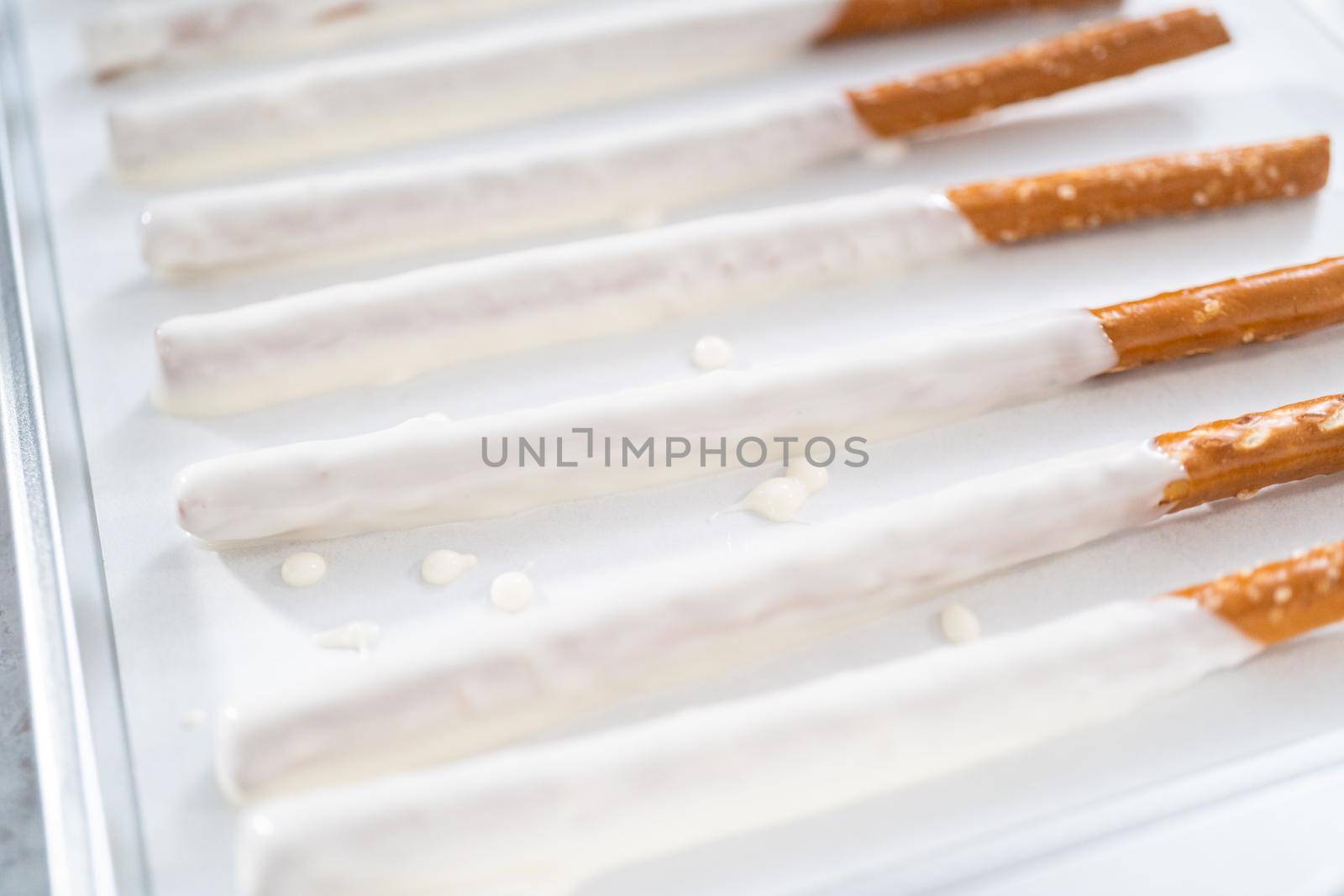 Dipping pretzel rods into the melted chocolate to prepare chocolate dipped pretzel rods for the July 4th celebration.