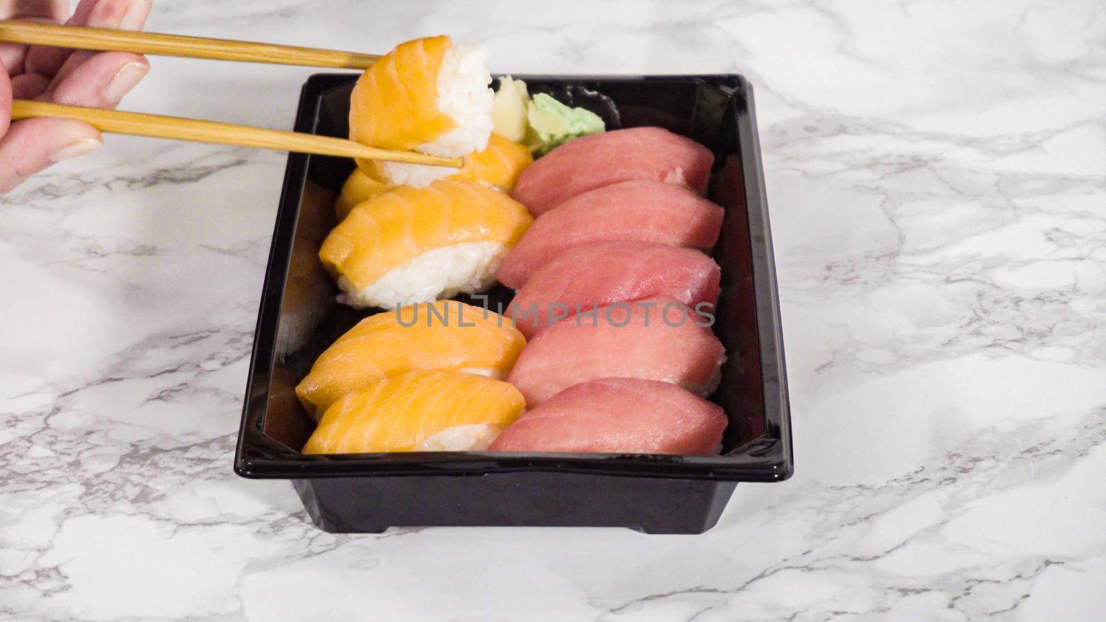 Pre-packaged variety of sushi and sushi rolls in a plastic tray.