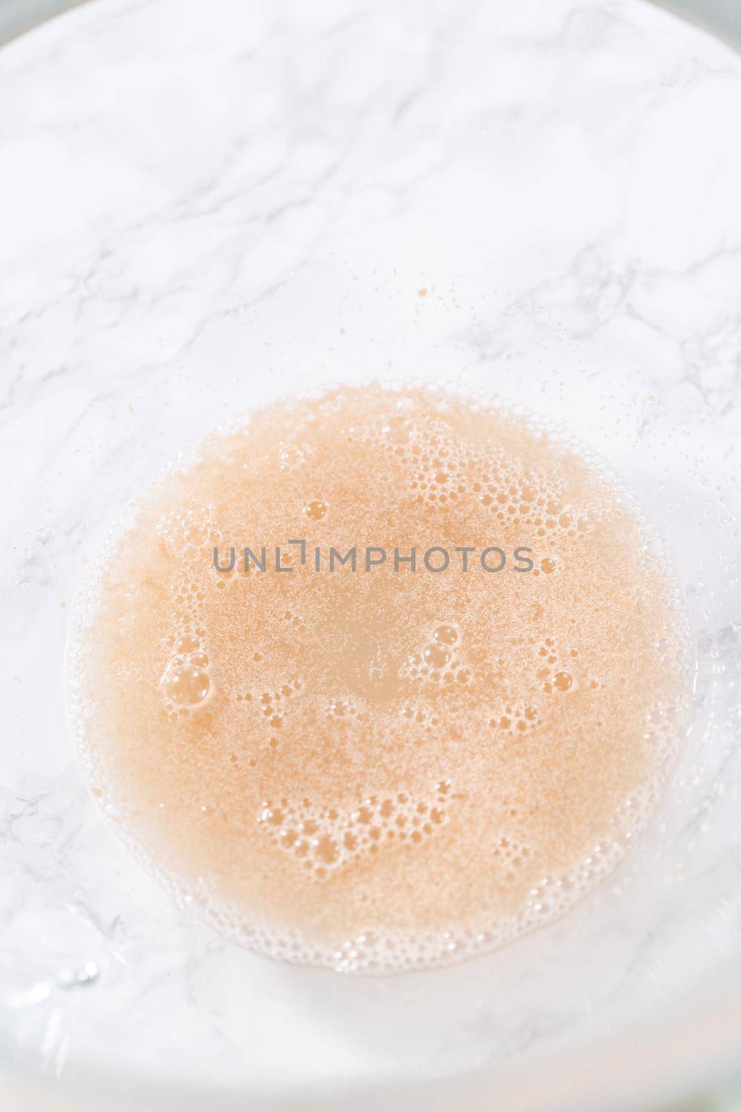 Activating dry yeast in a large glass mixing bowl to prepare the pizza dough.