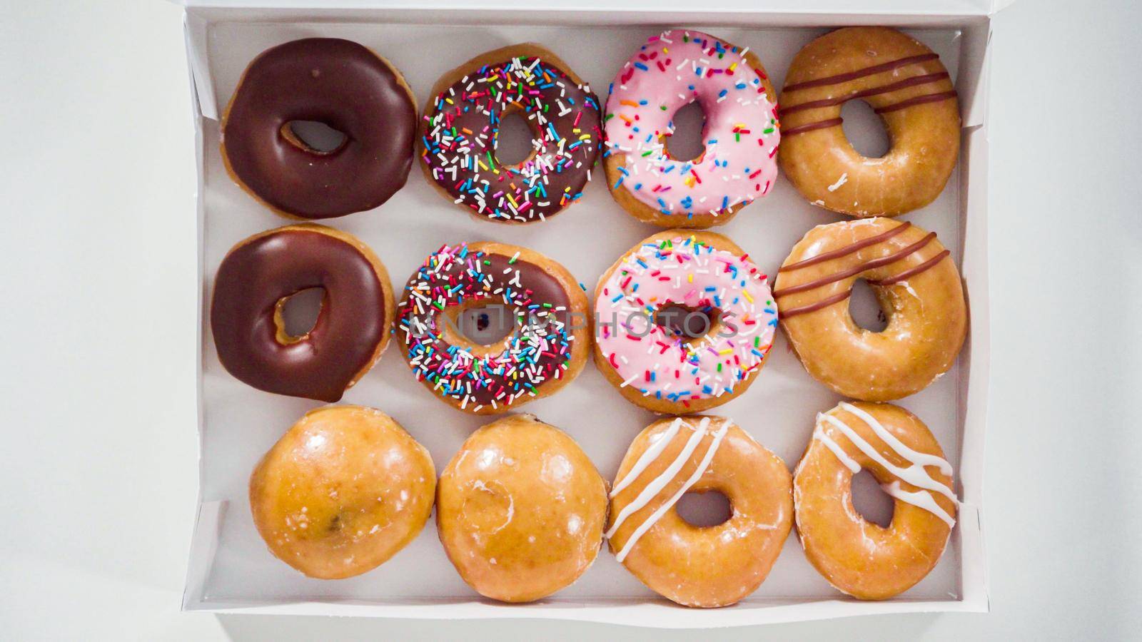 Flat lay. Variety of store-bought doughnuts in a white paper box.