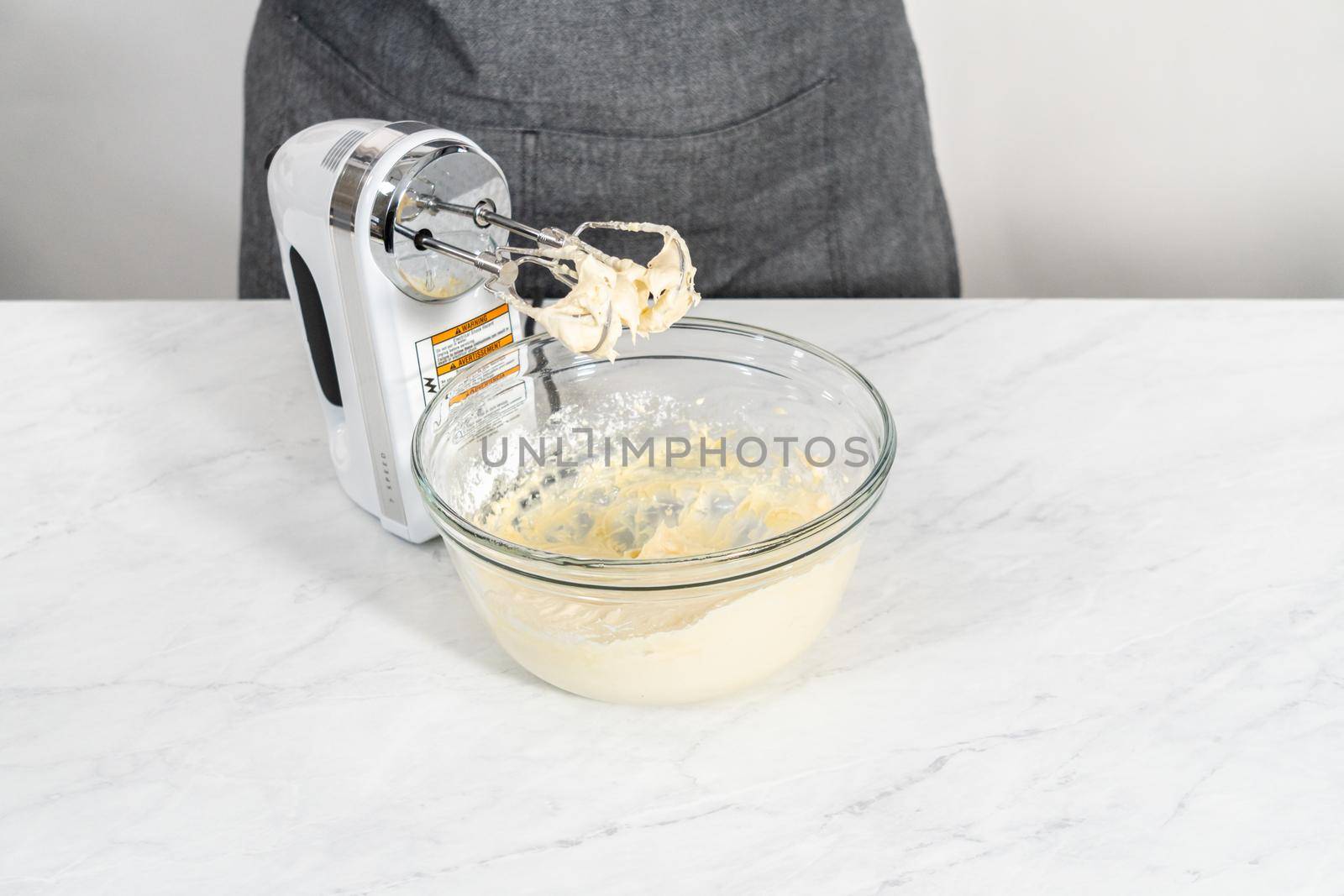 Mixing ingredients in a large glass mixing bowl to make the cream cheese filling for bundt cake.