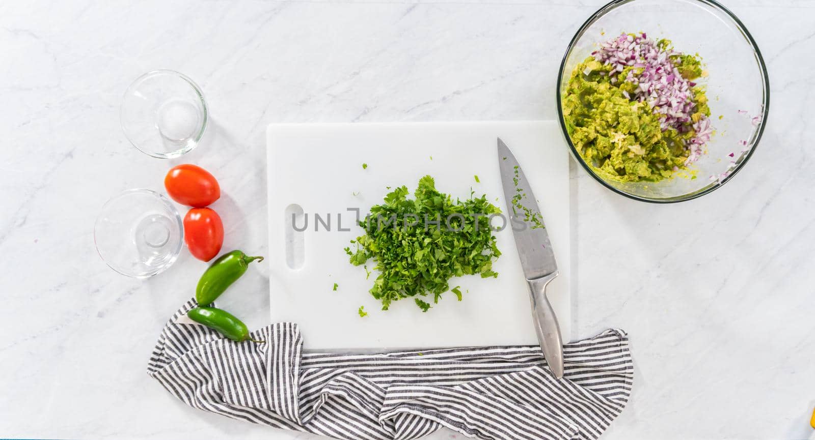 Flat lay. Cutting ingredients on a white cutting board to make classic guacamole dip.