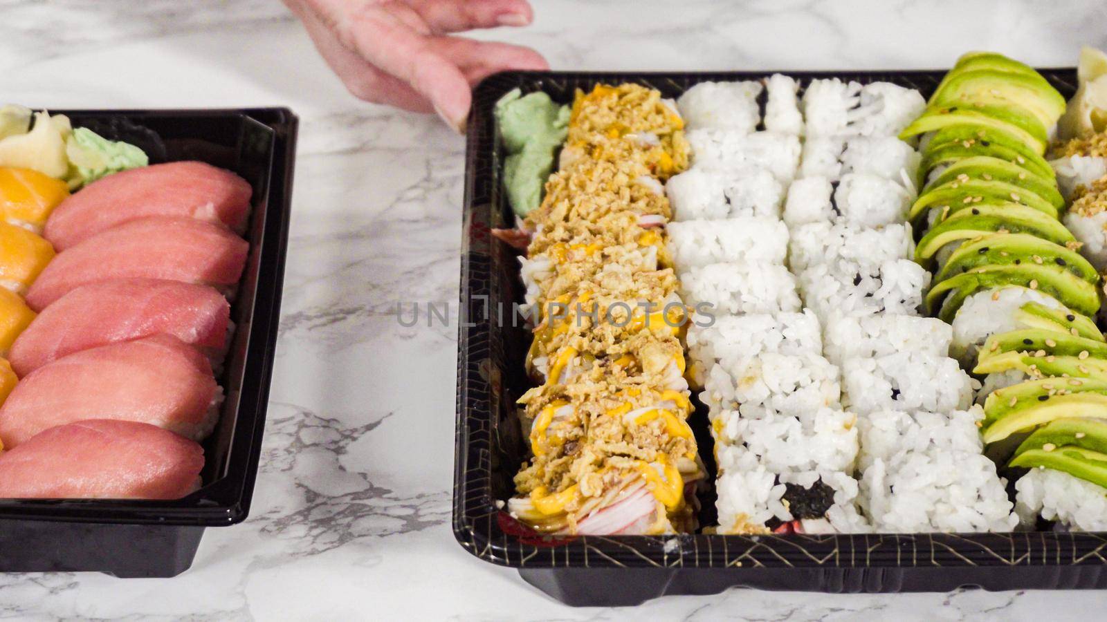 Pre-packaged variety of sushi and sushi rolls in a plastic tray.