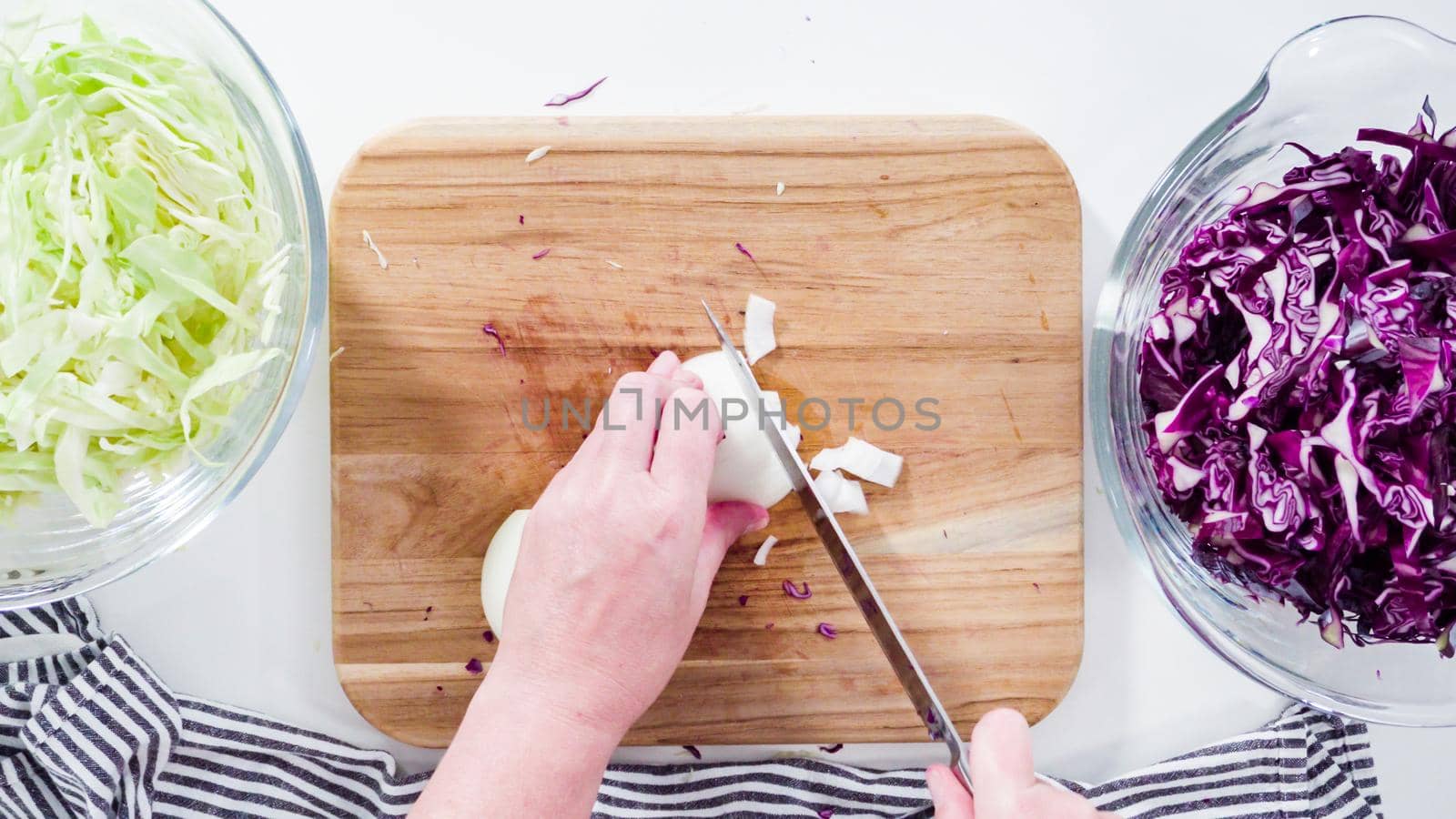 Flat lay. Step by step. Cubing organic yellow onion on a wooden cutting board.