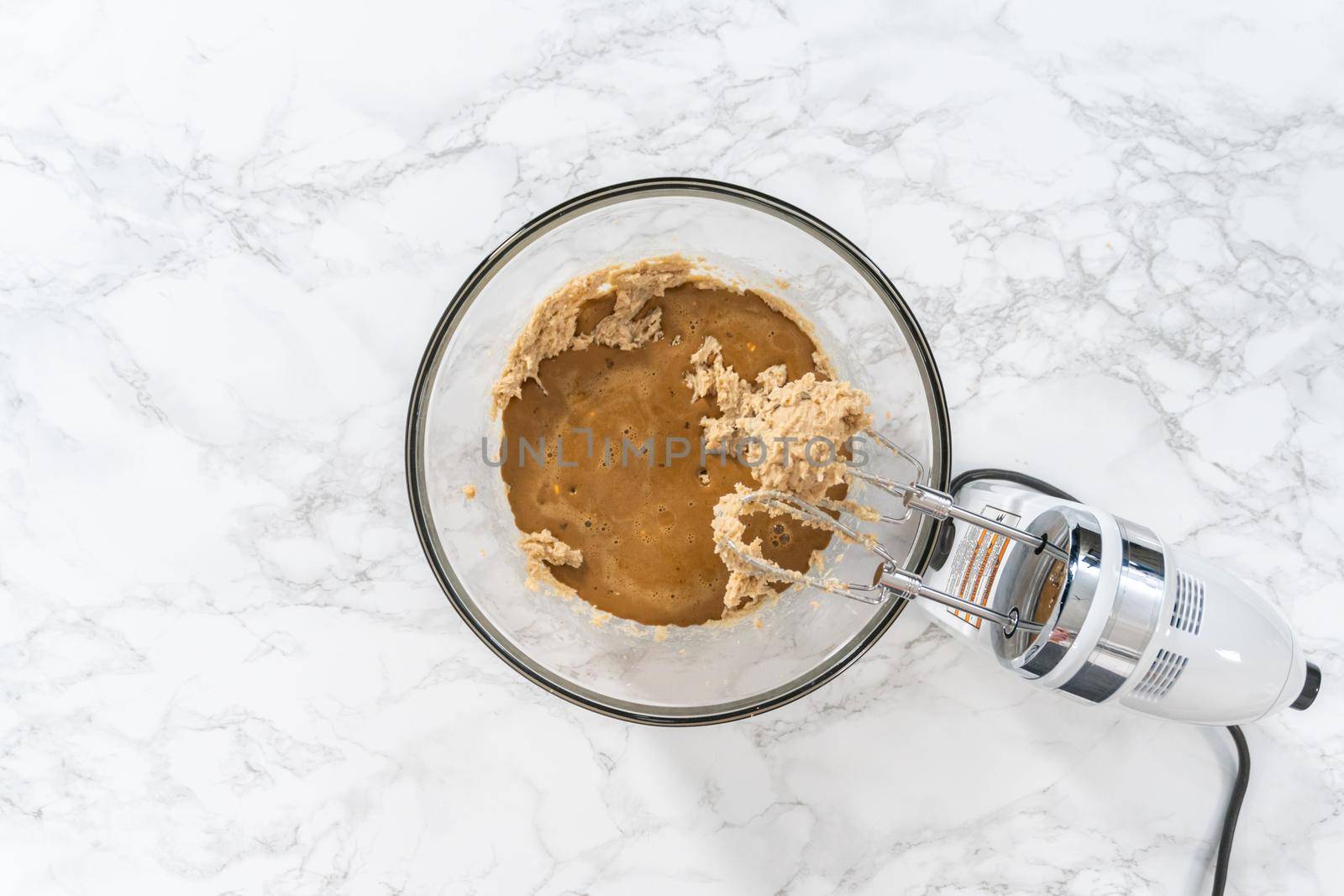 Mixing ingredients in a large glass mixing bowl to bake gingerbread cupcakes.