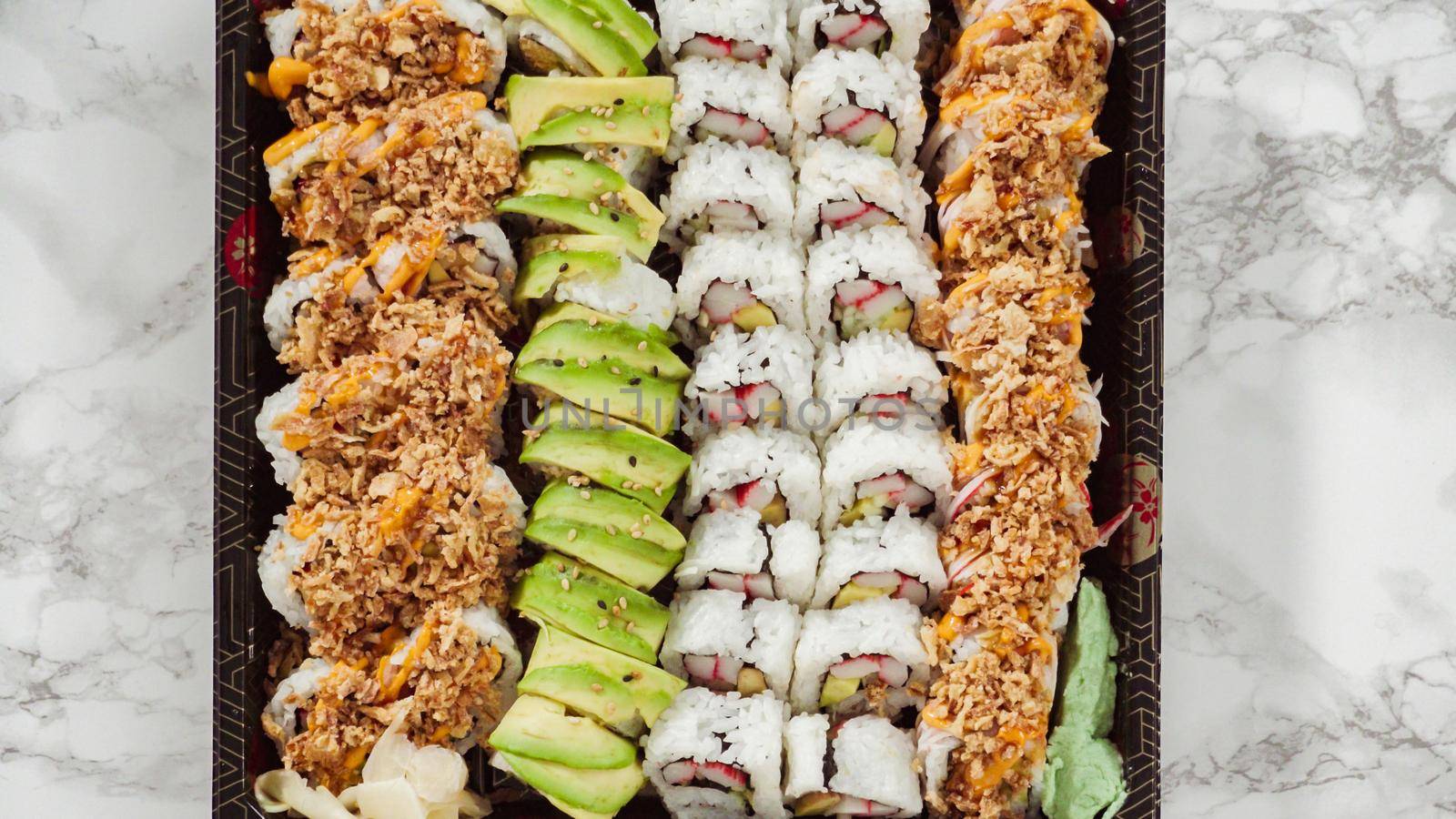 Flat lay. Pre-packaged variety of sushi and sushi rolls in a plastic tray.