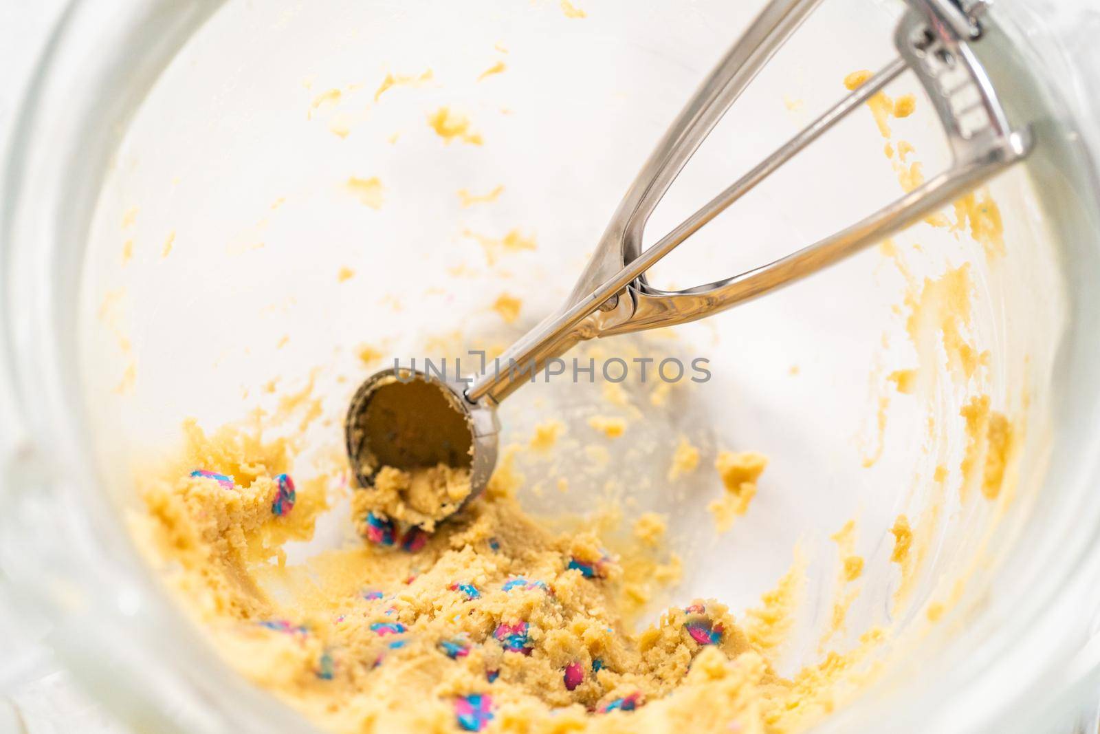 Scooping cookie dough with a dough scoop to bake unicorn chocolate chip cookies.