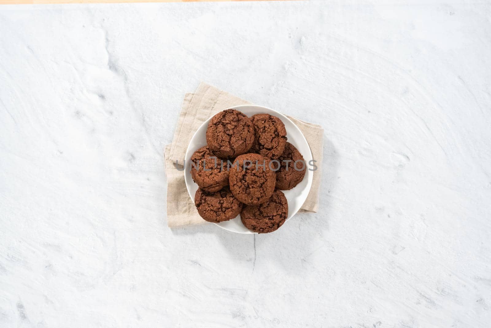 Flat lay. Freshly baked double chocolate chip cookies on a white plate.