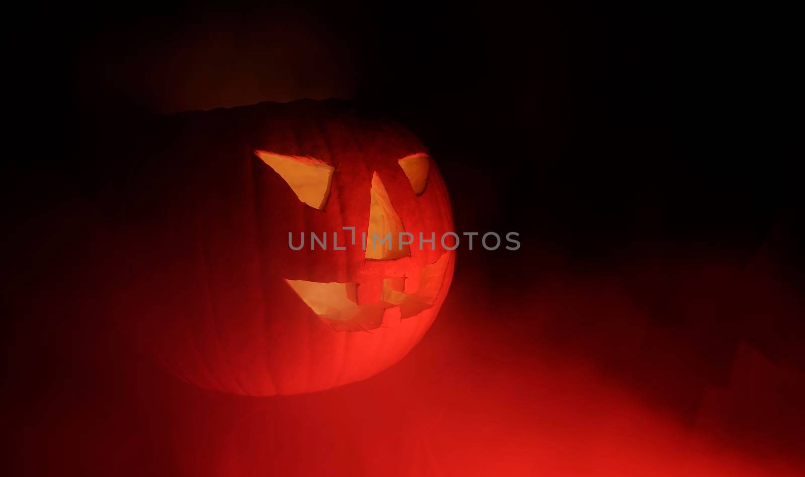 Evil Jack-o-lantern in red steam.  Halloween nightmare with carved pumpkin in the darkness. 