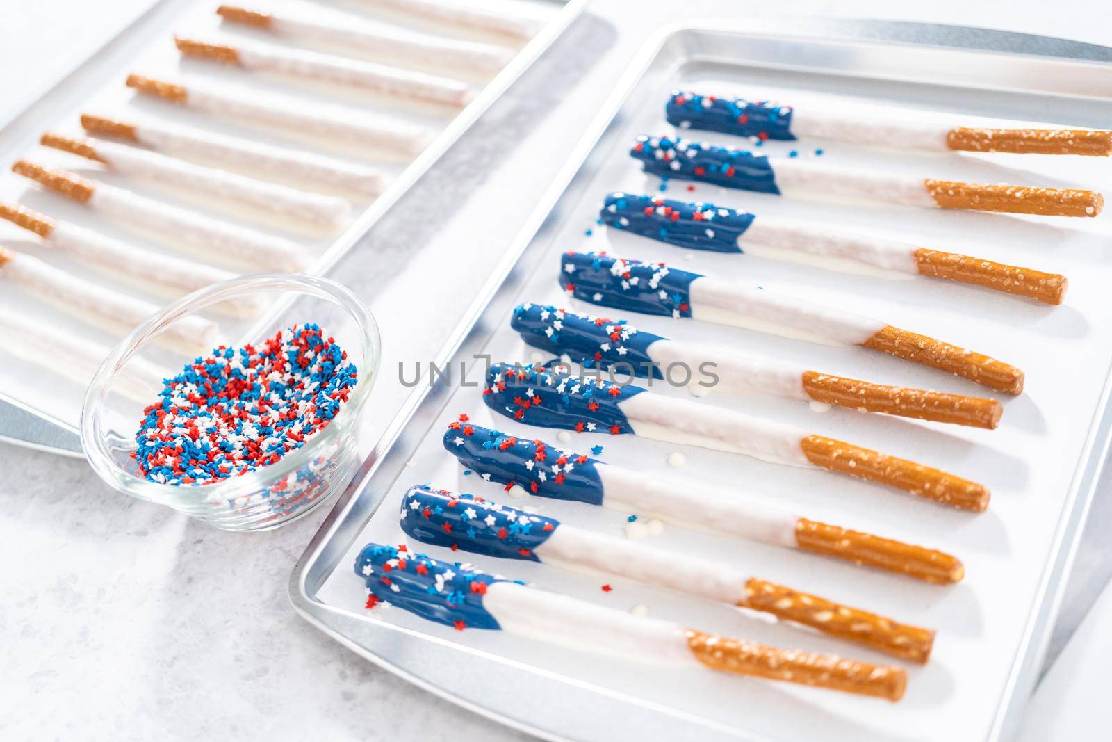 Dipping pretzel rods into the melted chocolate to prepare chocolate dipped pretzel rods for the July 4th celebration.