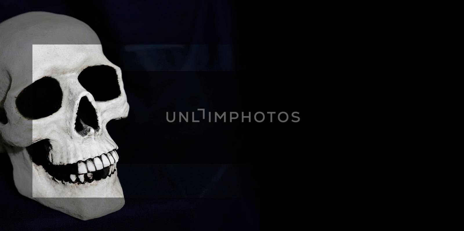 A skull made from resin on a dark background. The photo has been edited. Three layers of the same photo are put over each other