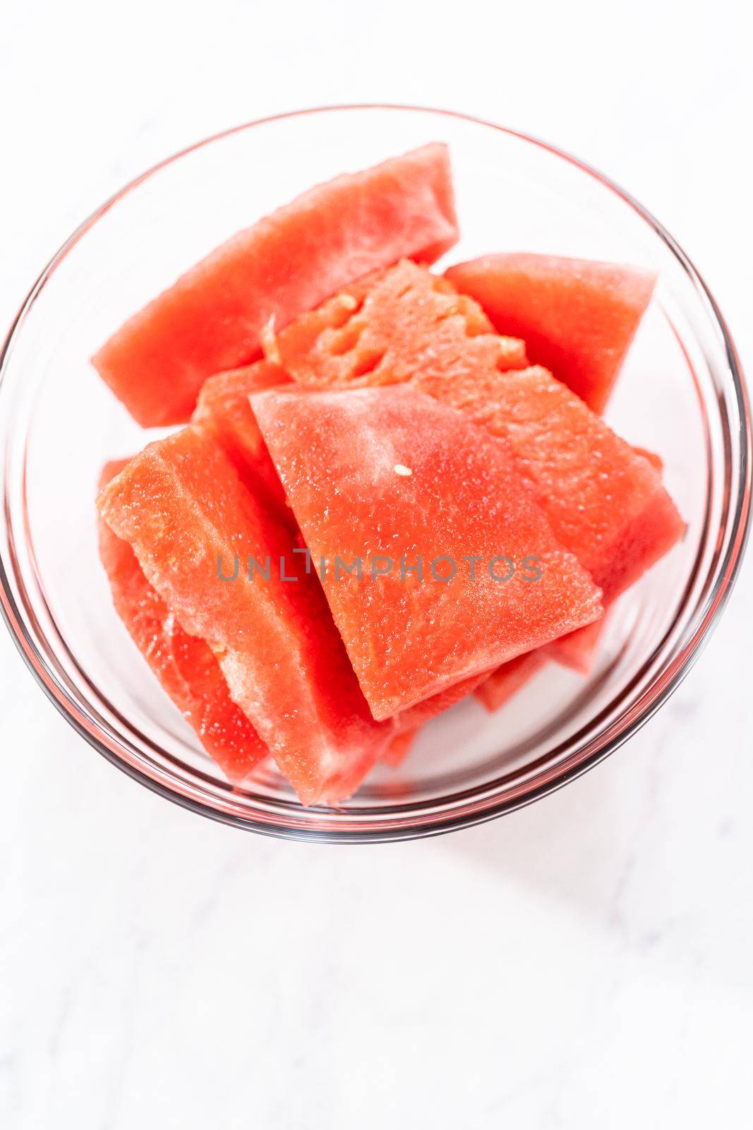 Cutting riped red watermelon to prepare frozen watermelon margarita.