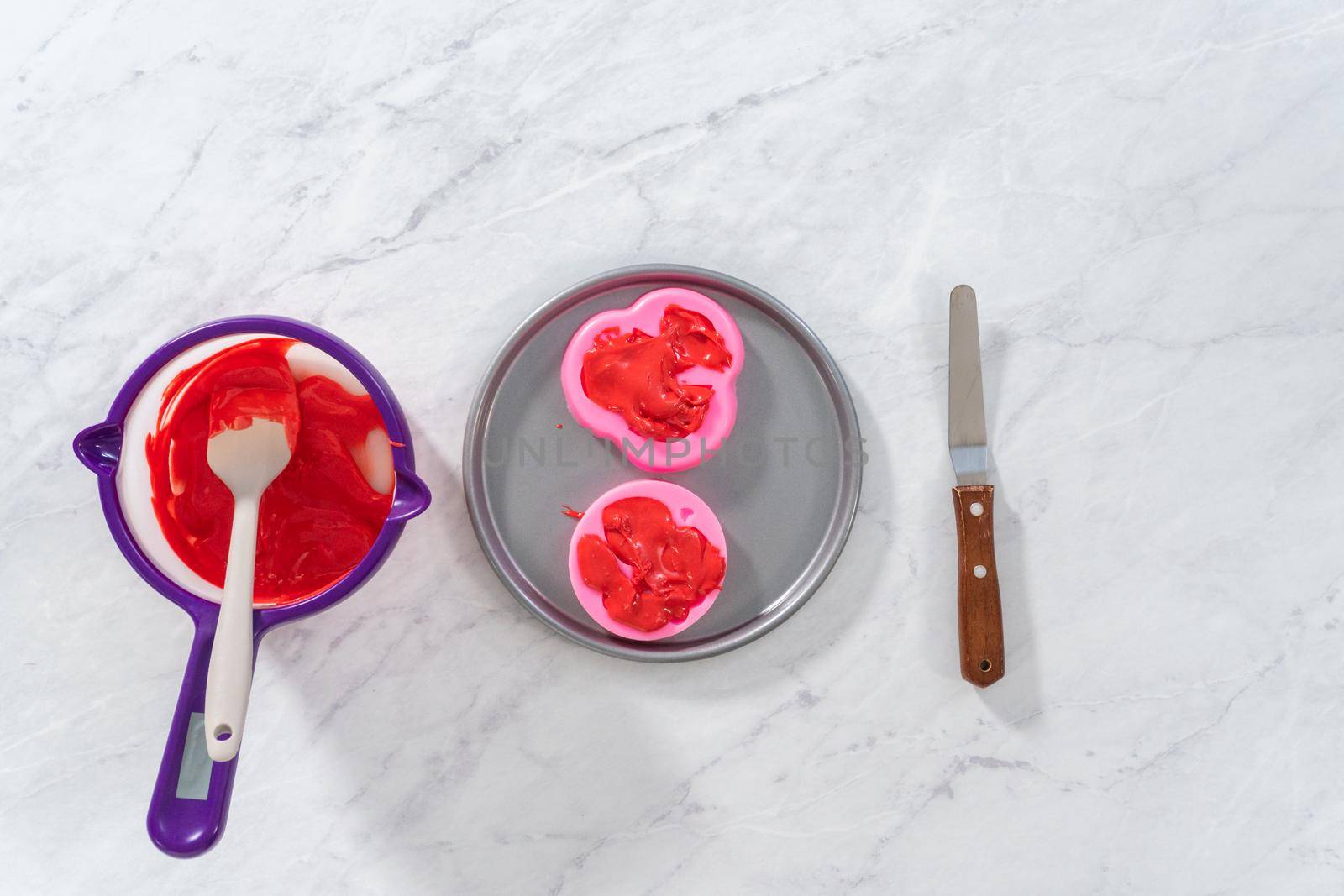 Flat lay. Filling silicone mold with melted chocolate to make chocolate lips and heart-shaped chocolates for Valentine's Day.