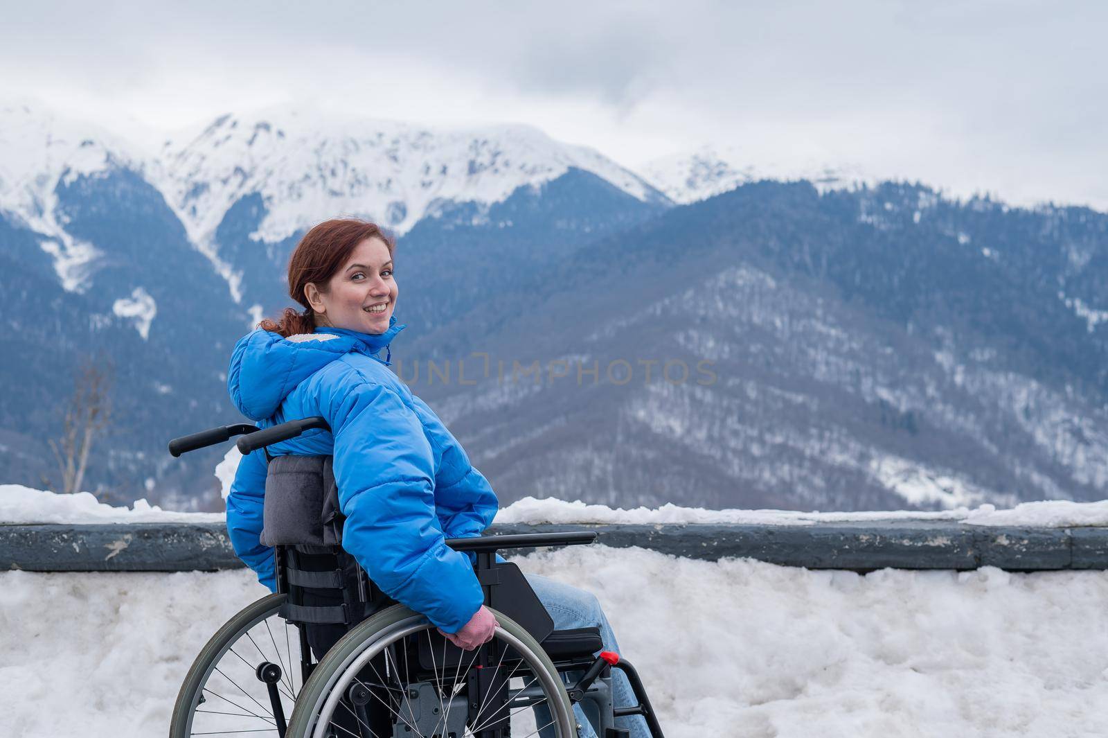 Caucasian woman in a wheelchair travels in the mountains in winter