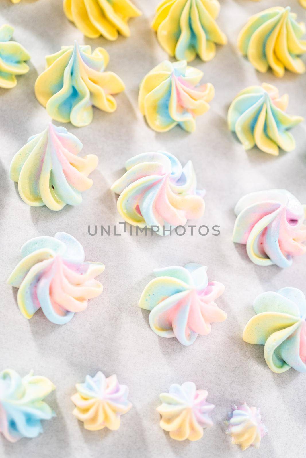 Freshly baked unicorn meringue cookies on a baking sheet with a parchment paper.