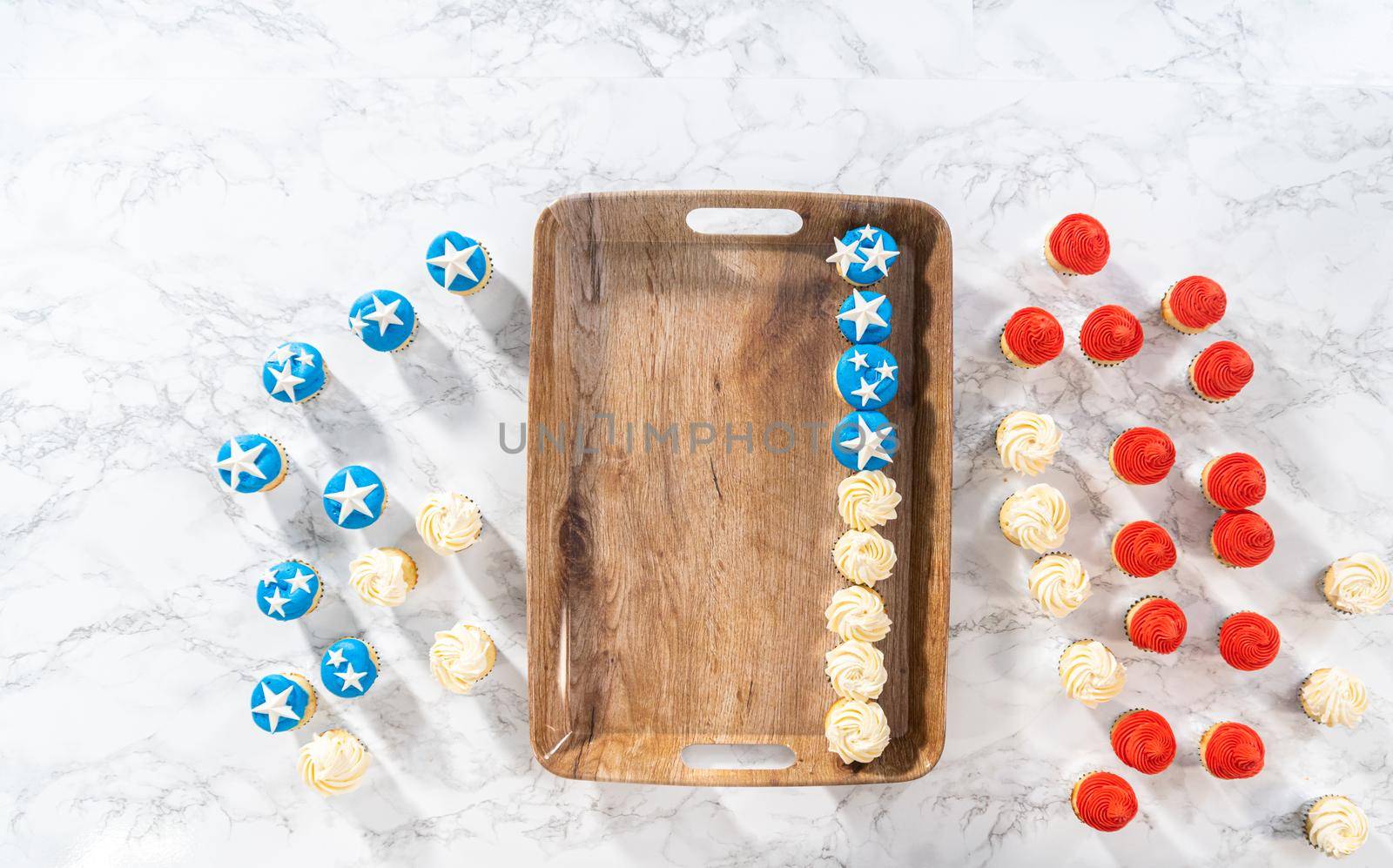 Flat lay. Arranging mini vanilla cupcakes in the shape of the American flag.