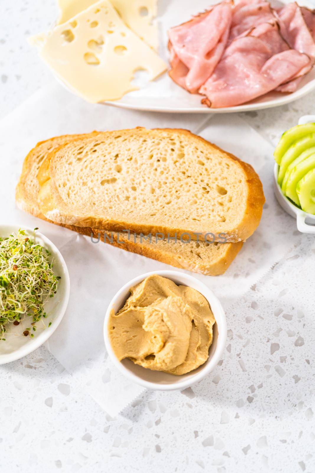 Measured ingredients in glass mixing bowls to make ham, cucumber, and sprout sandwiches.