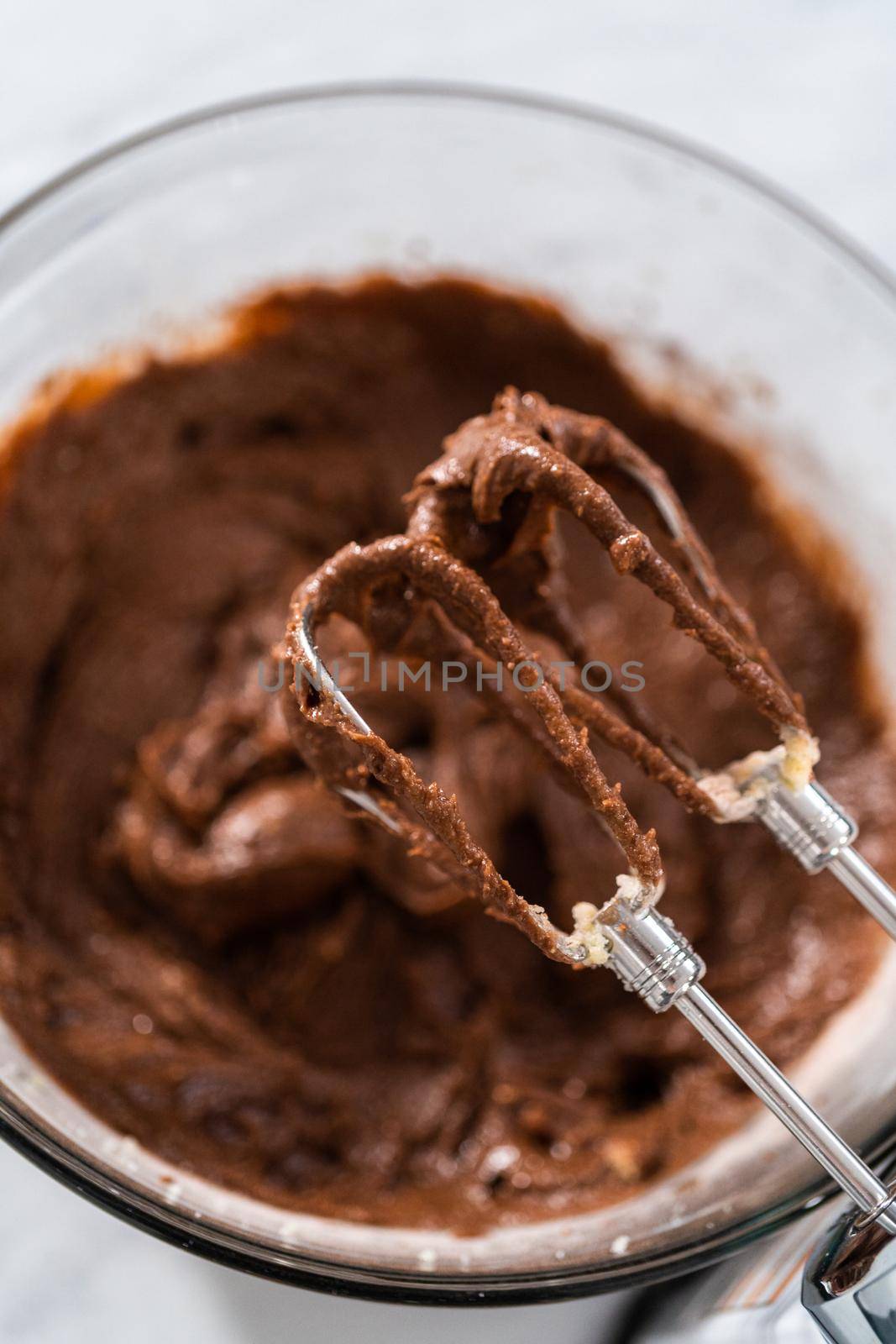 Mixing ingredients in a large glass mixing bowl to bake red velvet bundt cake with cream cheese glaze.