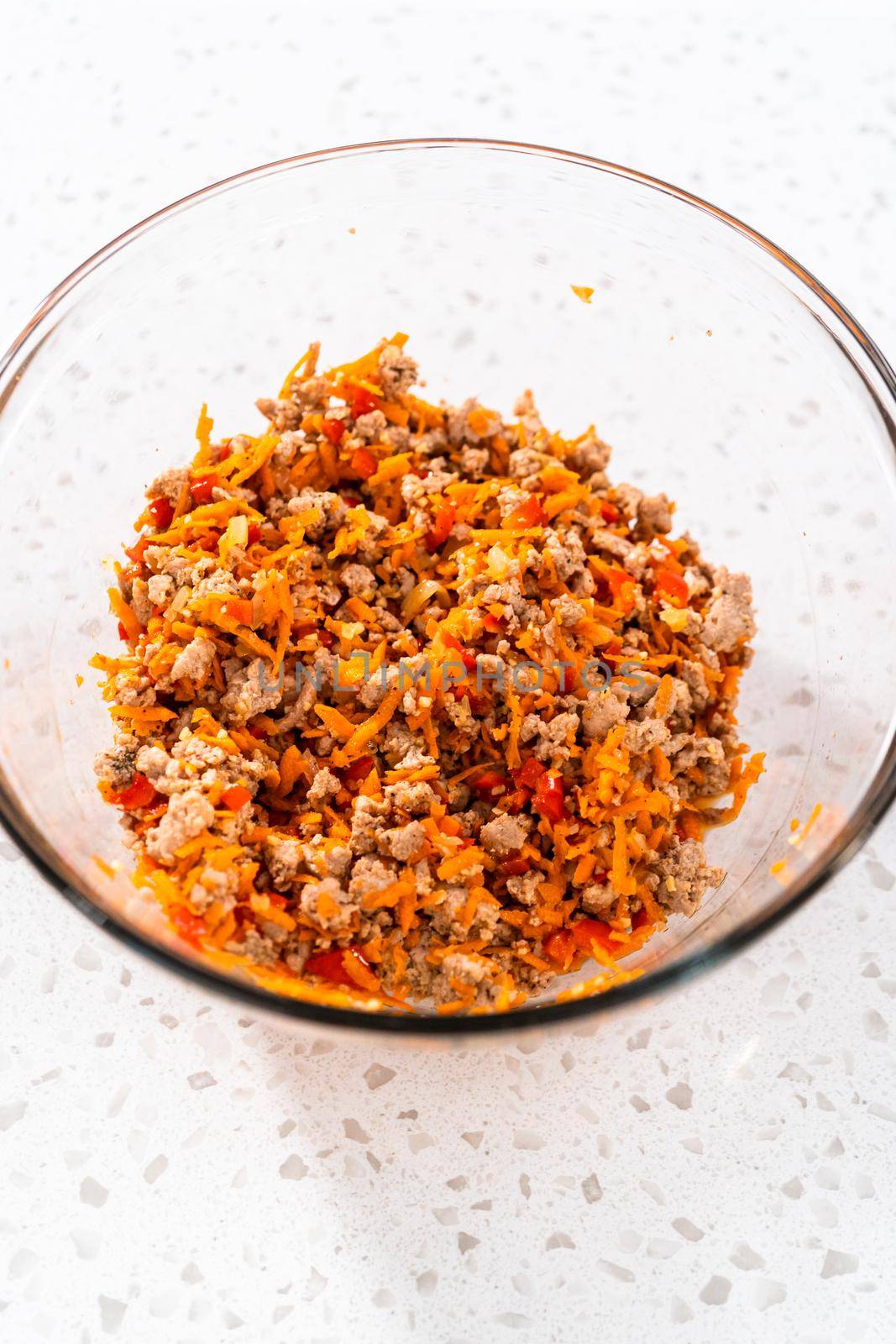 Mixing ingredients in a glass mixing bowl to prepare filling for turkey empanadas.