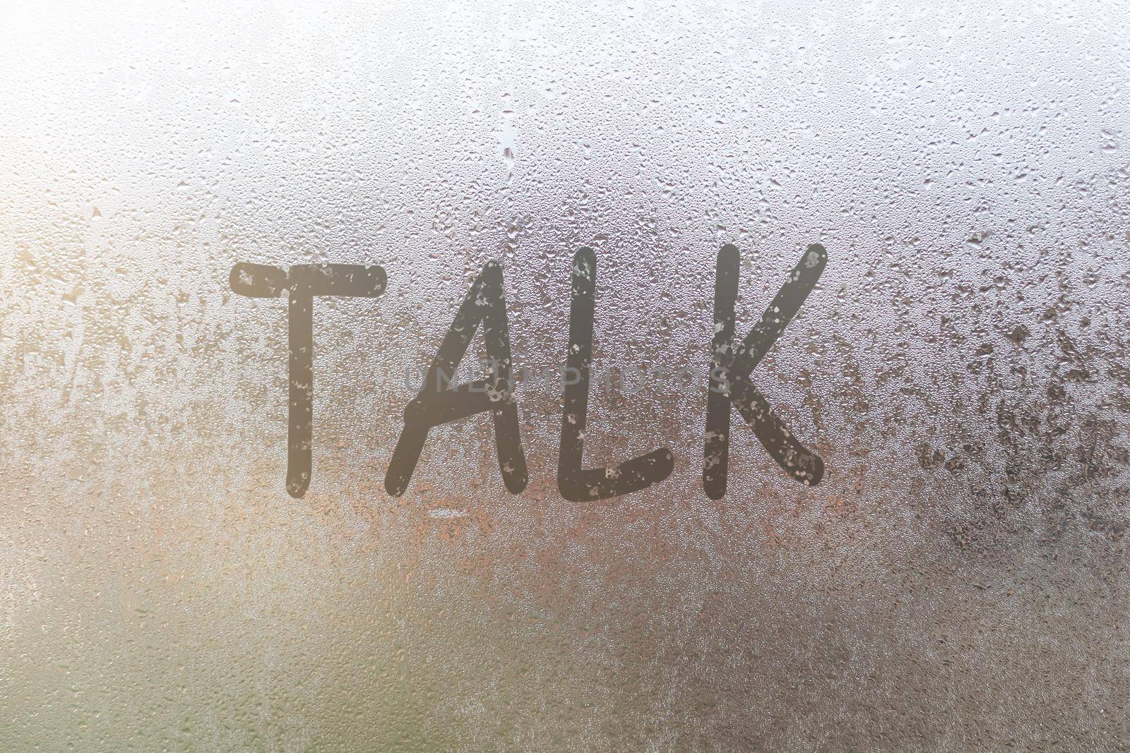 The word talk written on the sweaty glass of the window.
