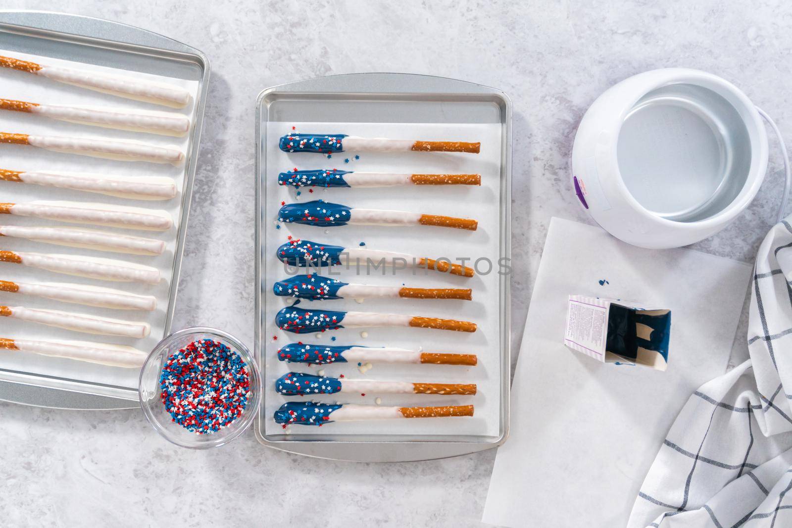 Flat lay. Dipping pretzel rods into the melted chocolate to prepare chocolate dipped pretzel rods for the July 4th celebration.
