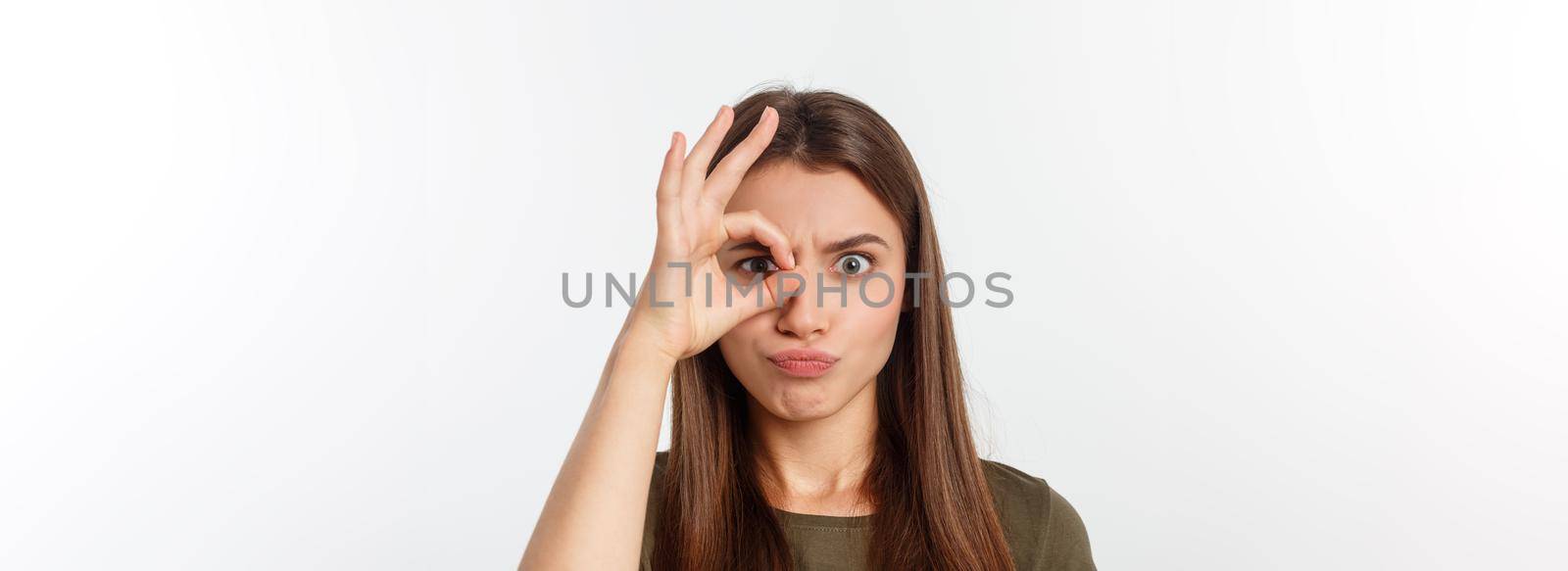 Close up portrait of cheerful, cute, stylish,attractive, trendy girl making binoculars with fingers, isolated on grey background, having good mood.