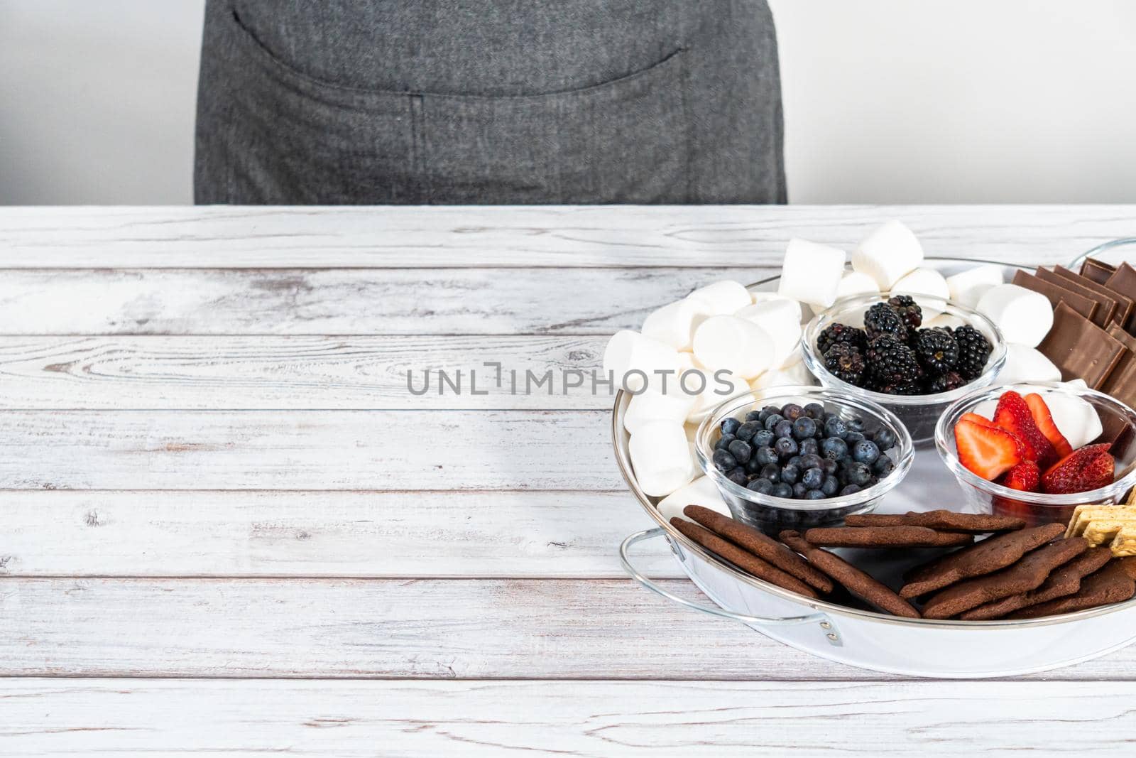 Arranging fruit s'mores charcuterie board on a white tray.