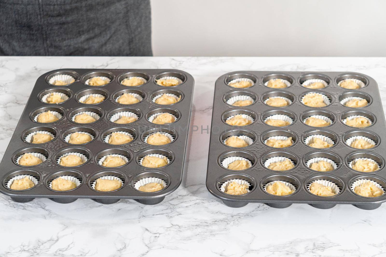 Scooping cupcake batter with dough scoop into a baking pan with liners to bake American flag mini cupcakes.