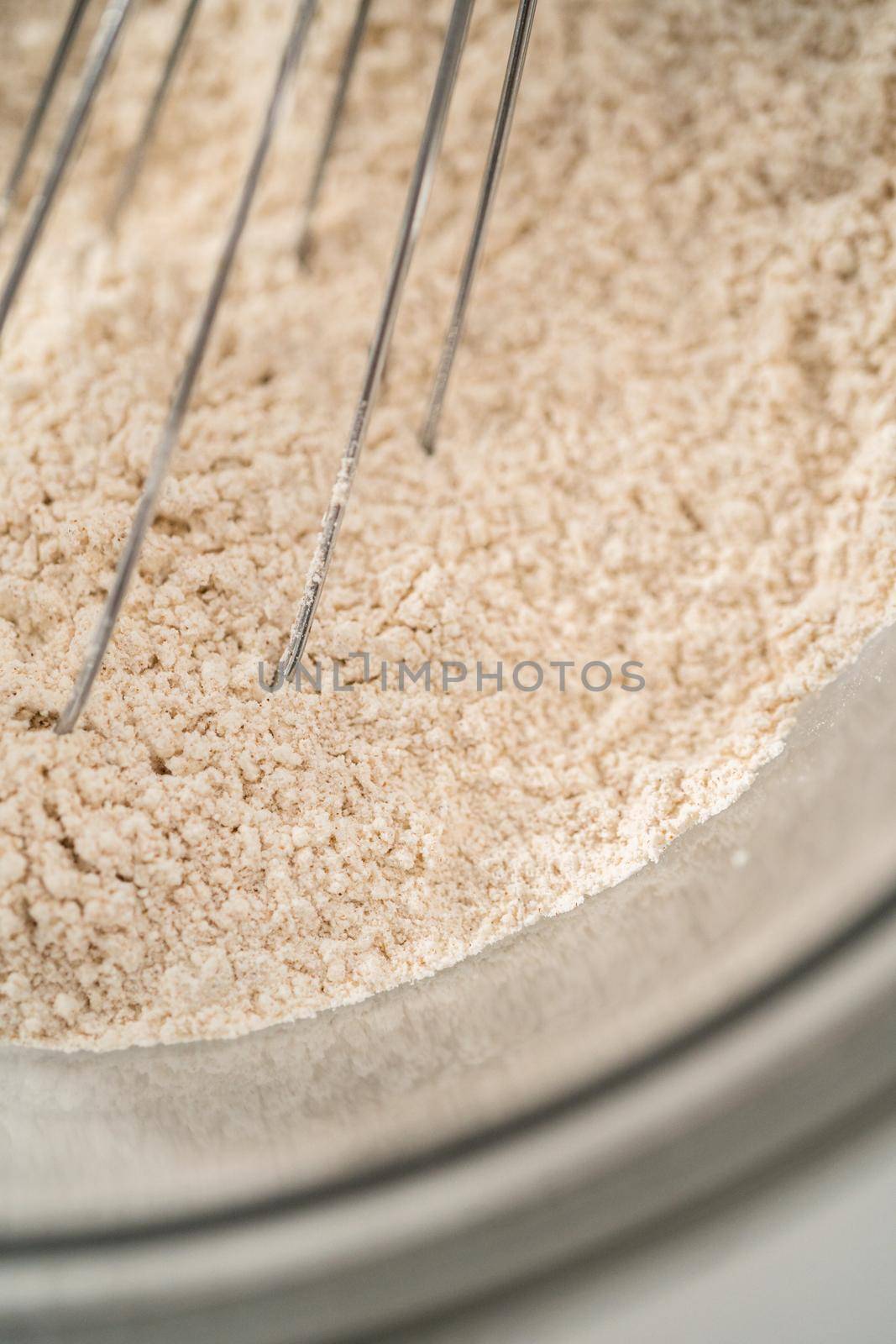 Mixing ingredients in a large glass mixing bowl to bake gingerbread cupcakes.