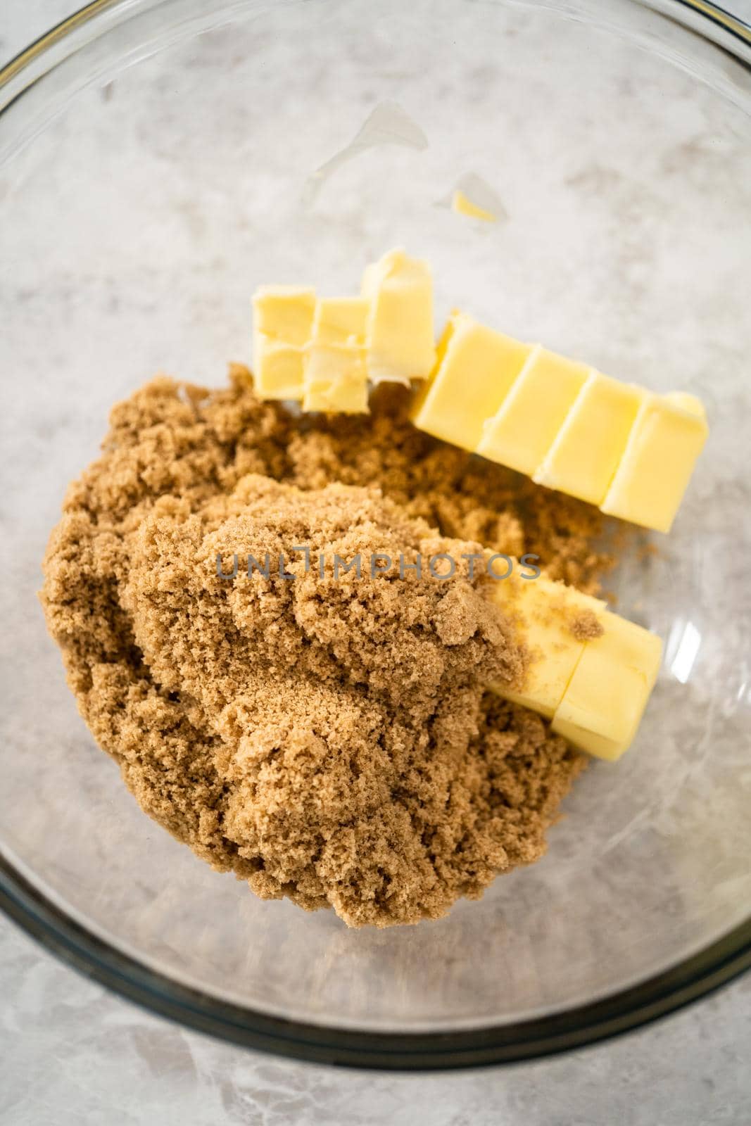 Mixing ingredients in a large glass mixing bowl with a kitchen mixer to bake chocolate cookies with peppermint chips.