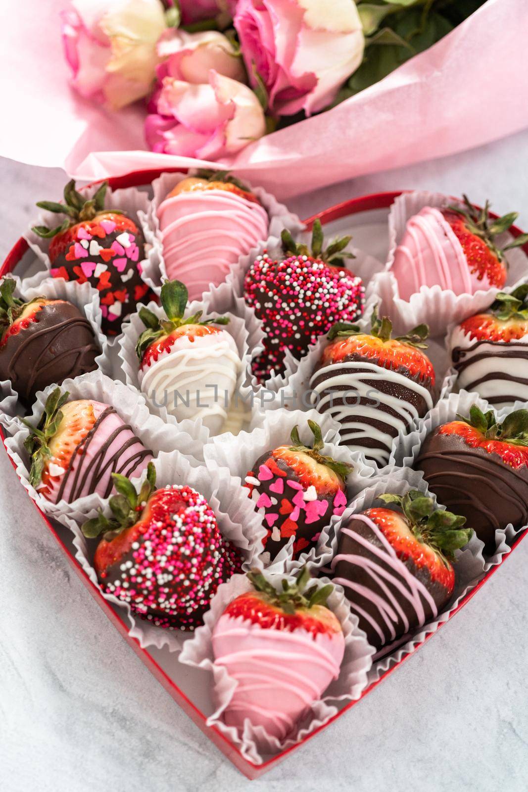 Heart shaped box with assorted chocolate covered strawberries on a white background.