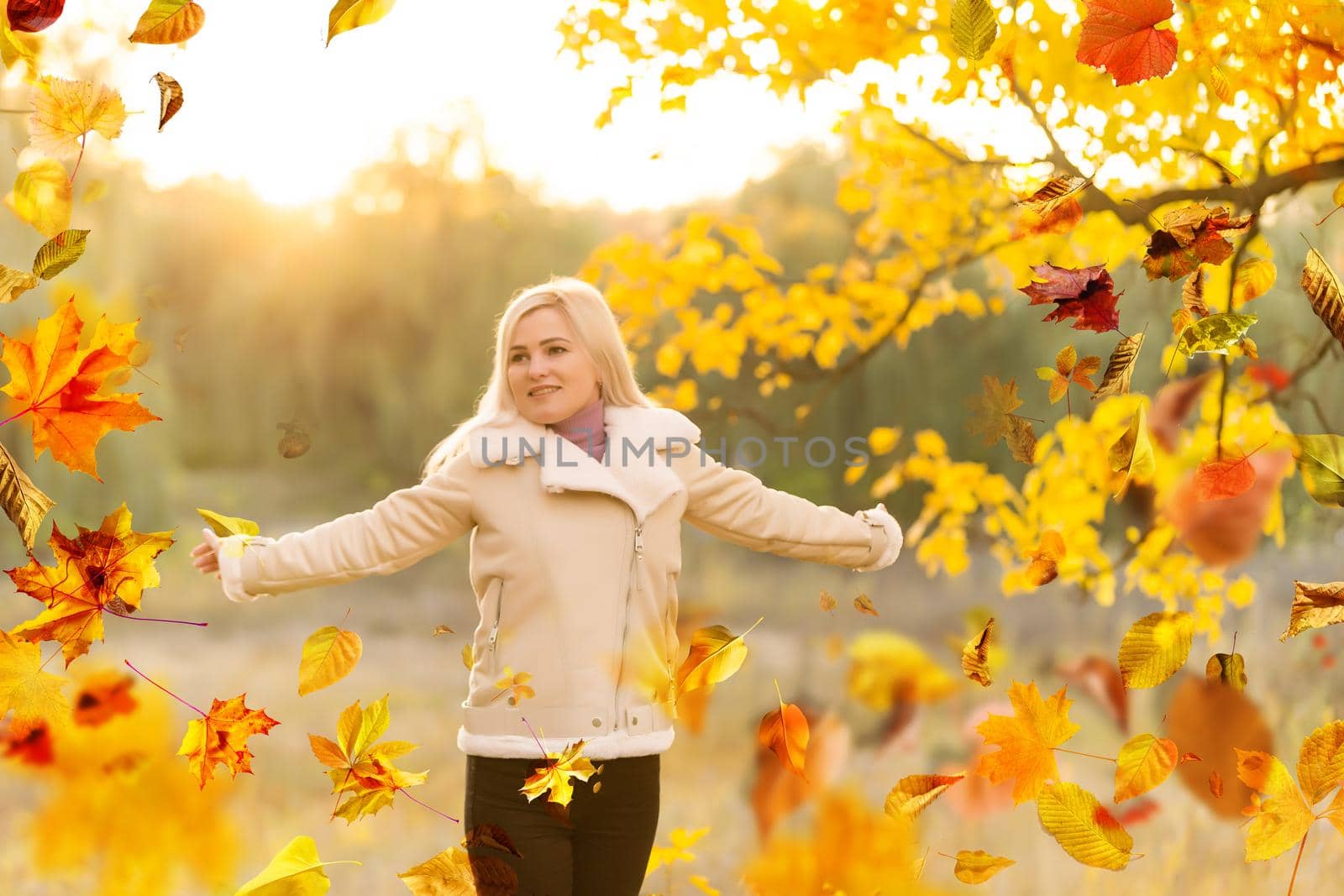 Beautiful girl walking outdoors in autumn. Smiling girl collects yellow leaves in autumn. Young woman enjoying autumn weather. High quality photo