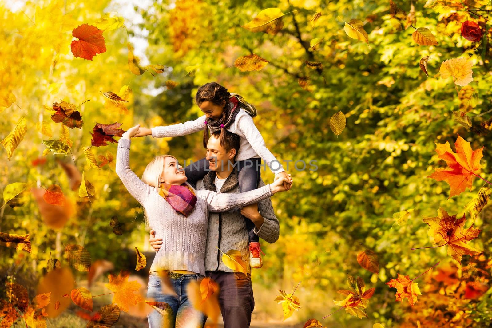 family, childhood, season and people concept - happy family playing with autumn leaves in park by Andelov13