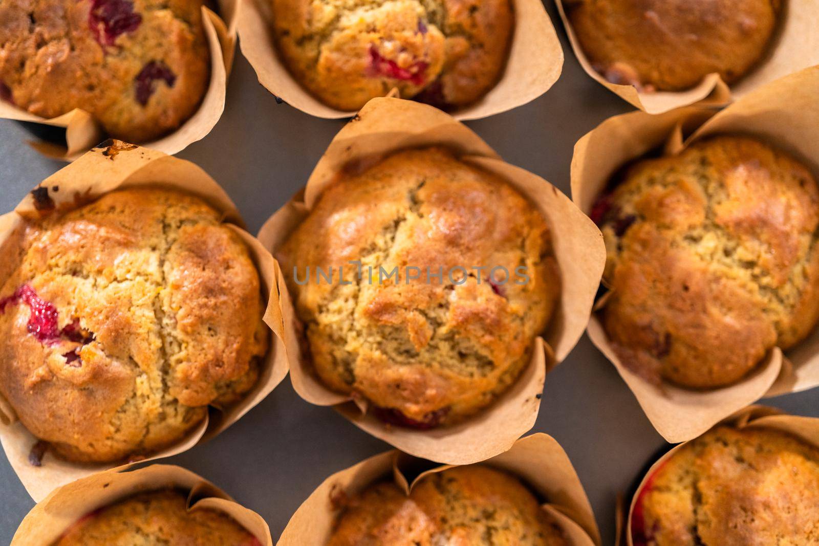 Freshly baked cranberry muffins in brown paper muffin cups.